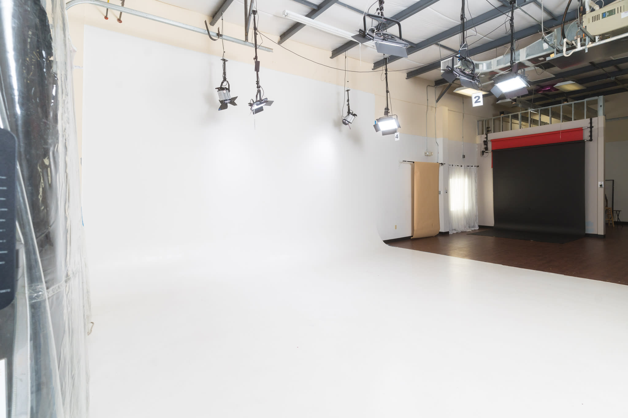 A child stands in the center of a studio while another child watches, as an adult photographer captures the scene.