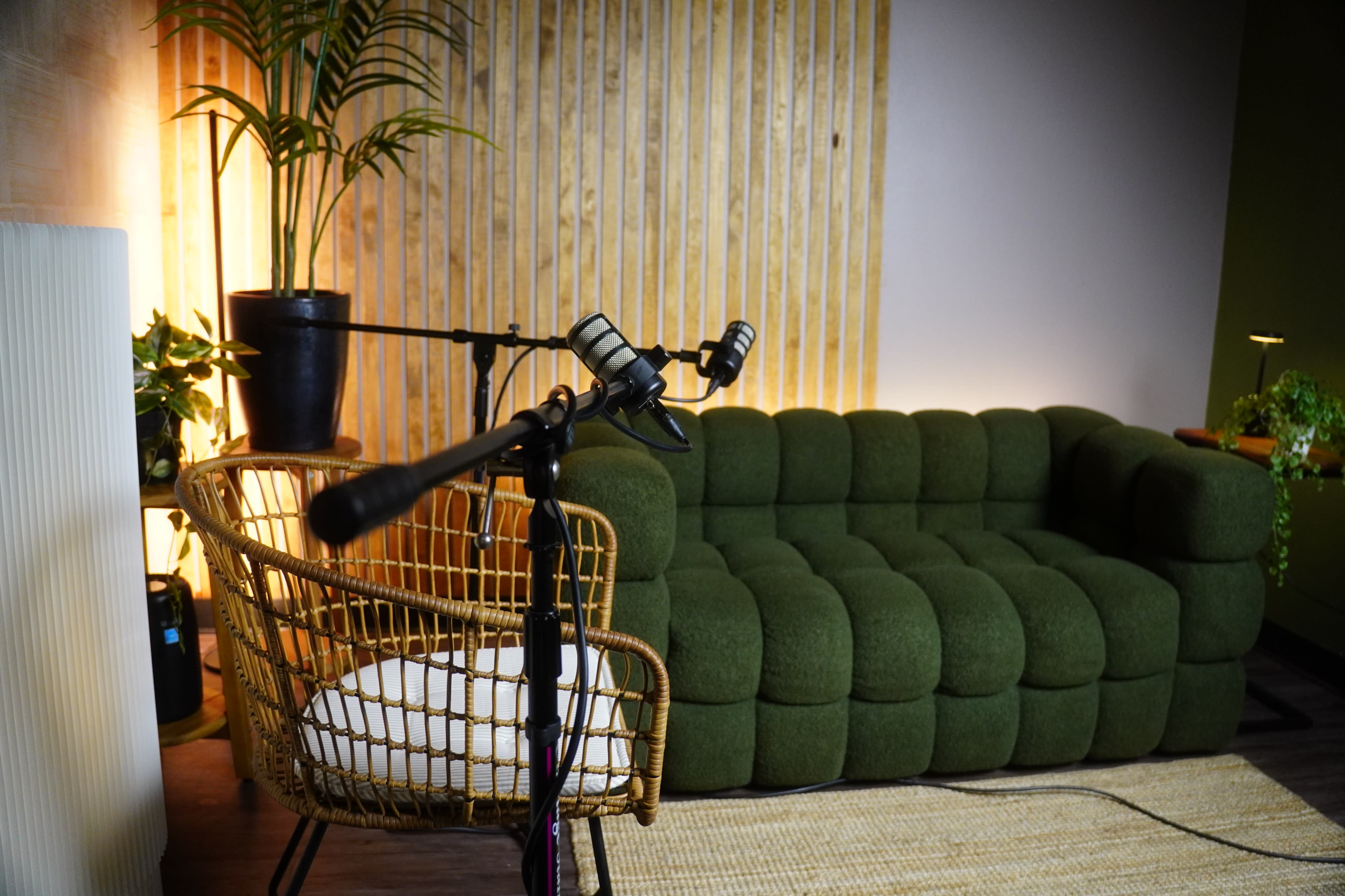 A person is laughing while sitting in a chair, speaking into a microphone during a podcast recording session.
