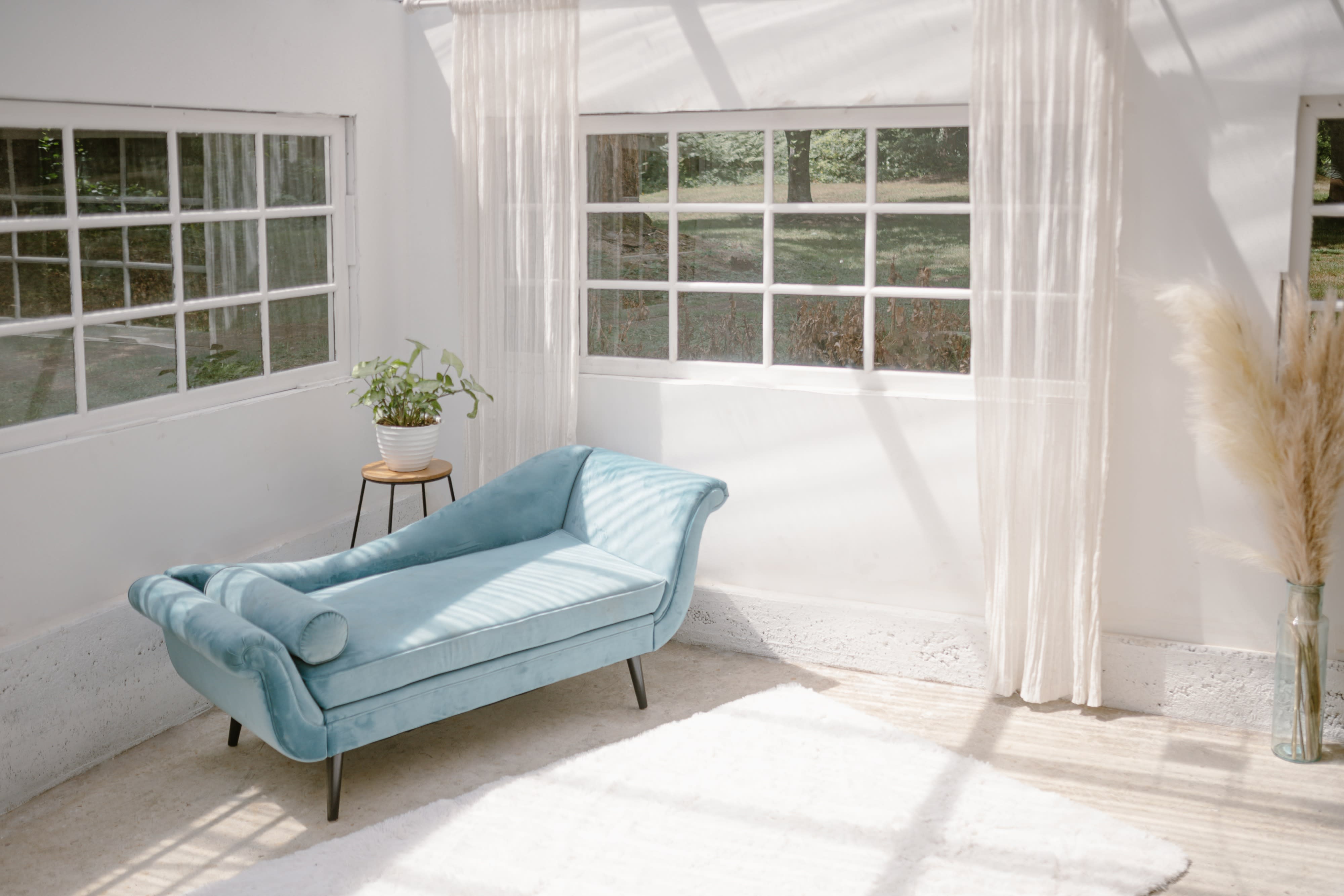 A couple sits on a teal sofa, with the pregnant woman reclining against her partner while they share a joyful moment.