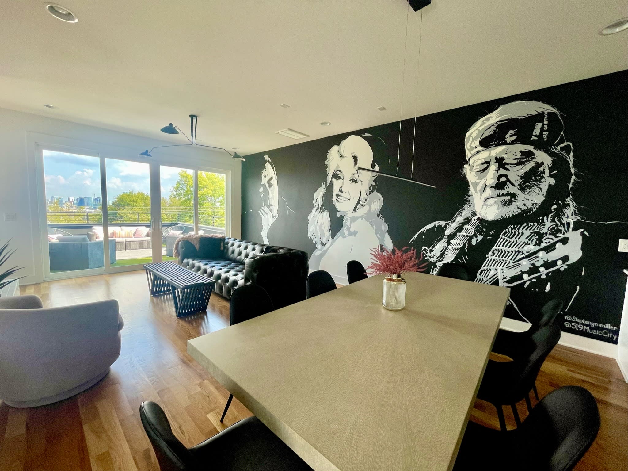 A table is set with a variety of dishes and a floral arrangement, featuring a mural of a man in the background.