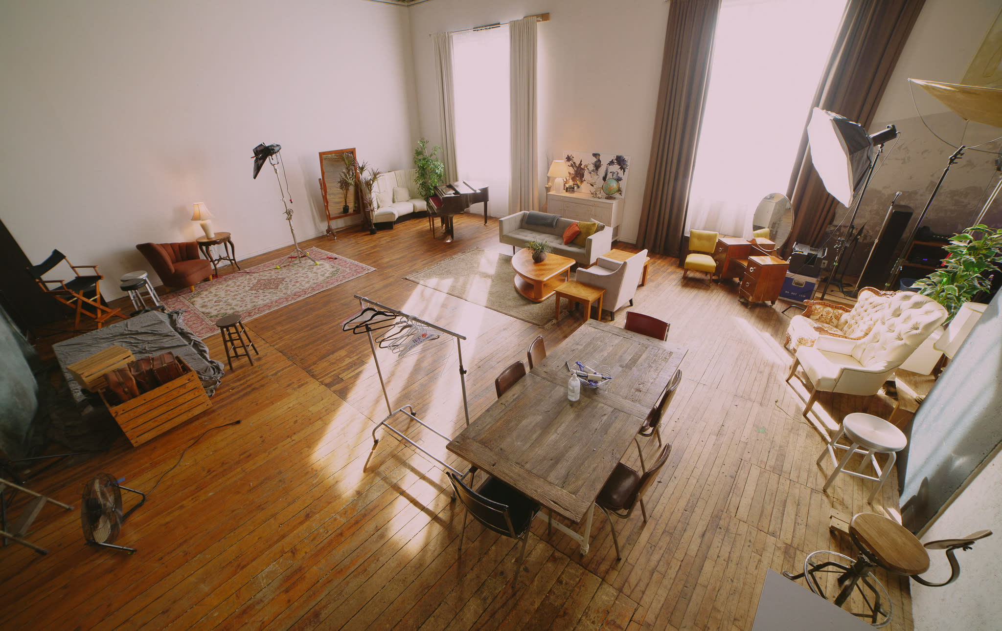 A cameraman captures a discussion among several people seated on vintage couches in a decorated studio space.