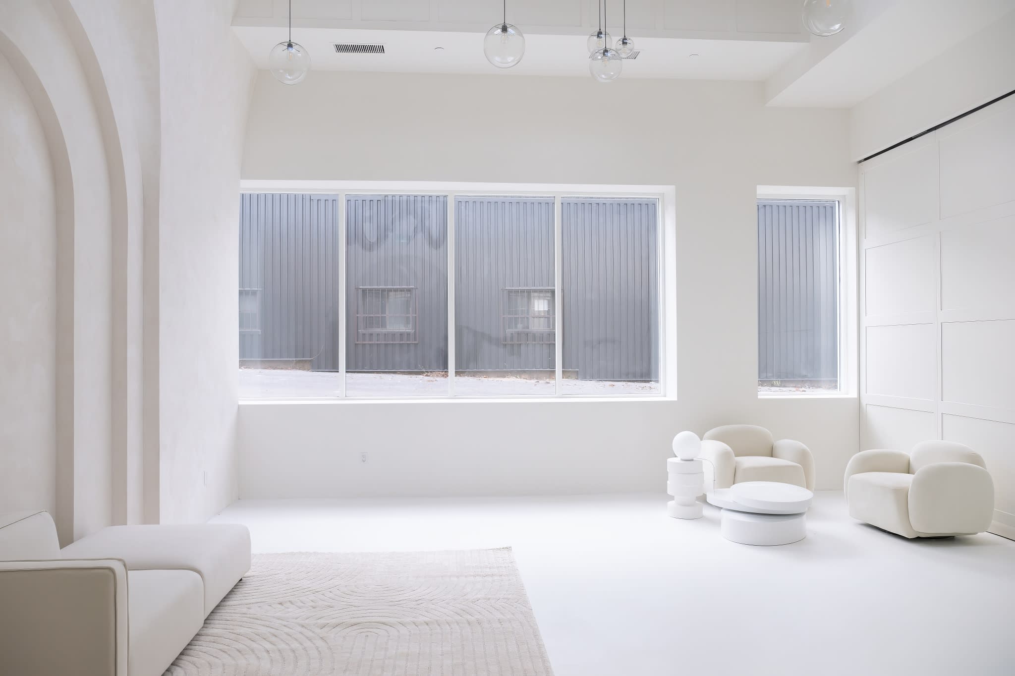 A minimalist photo shoot takes place in a bright, airy room with soft white curtains and simple furniture.