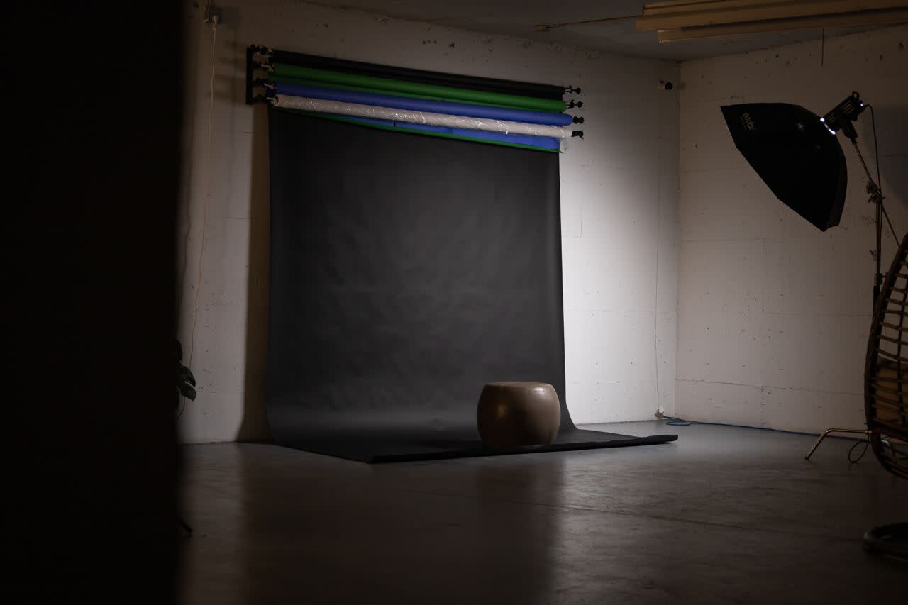 A couple poses in matching cloaks during a photoshoot against a plain backdrop.
