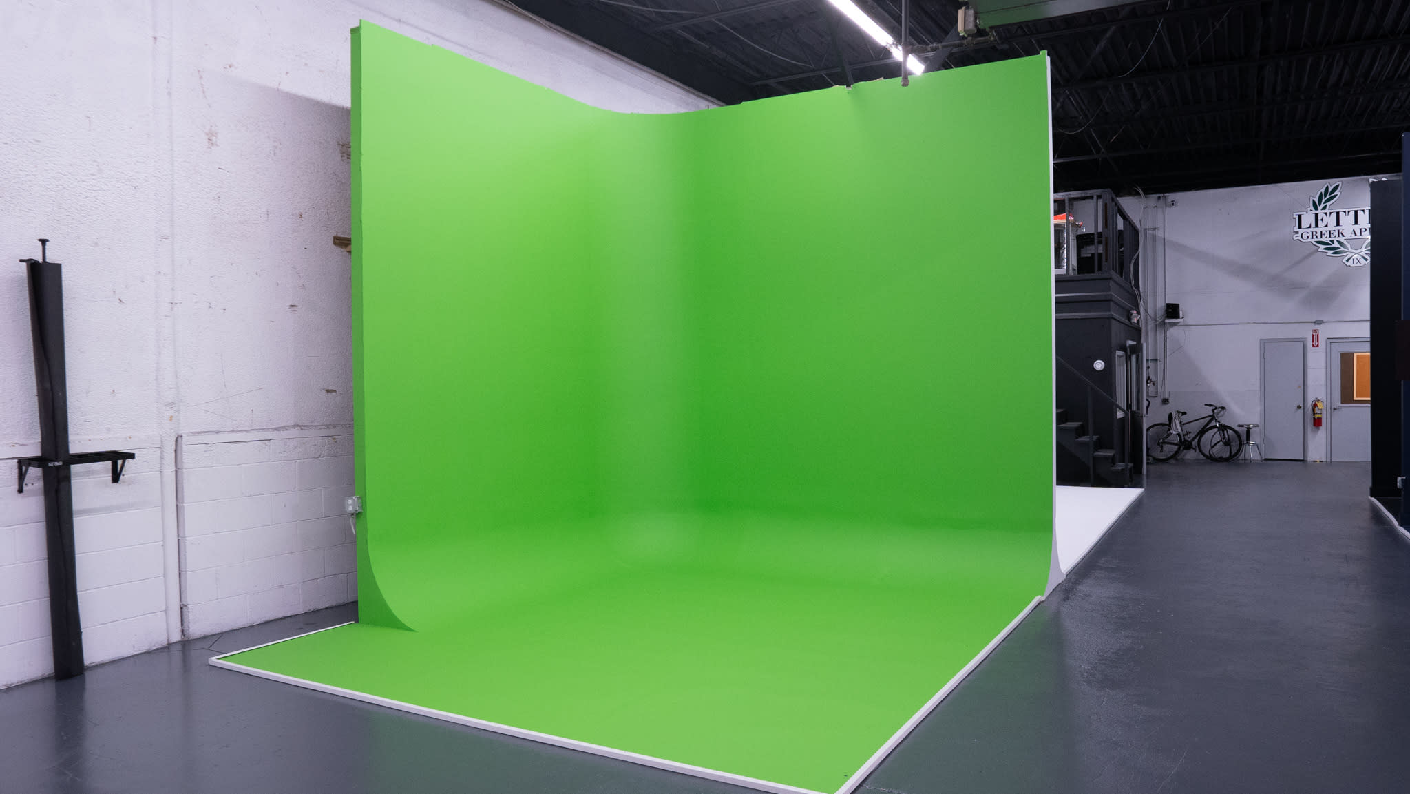 A green screen setup for a video shoot features a keyboard on a white table, with two softbox lights positioned on either side.