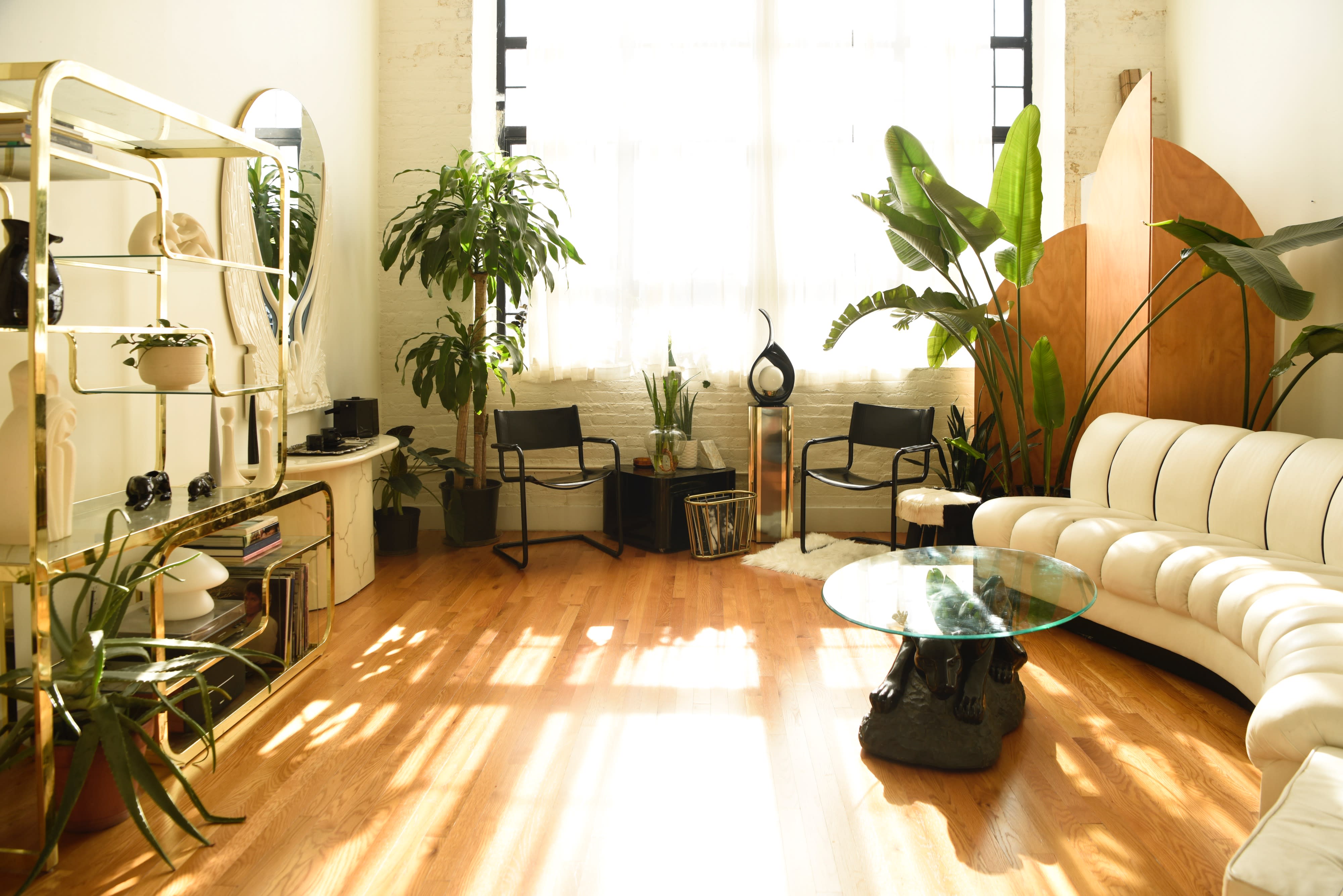 A person in a pink outfit lounges on a white couch while reading a magazine in a sunlit room.