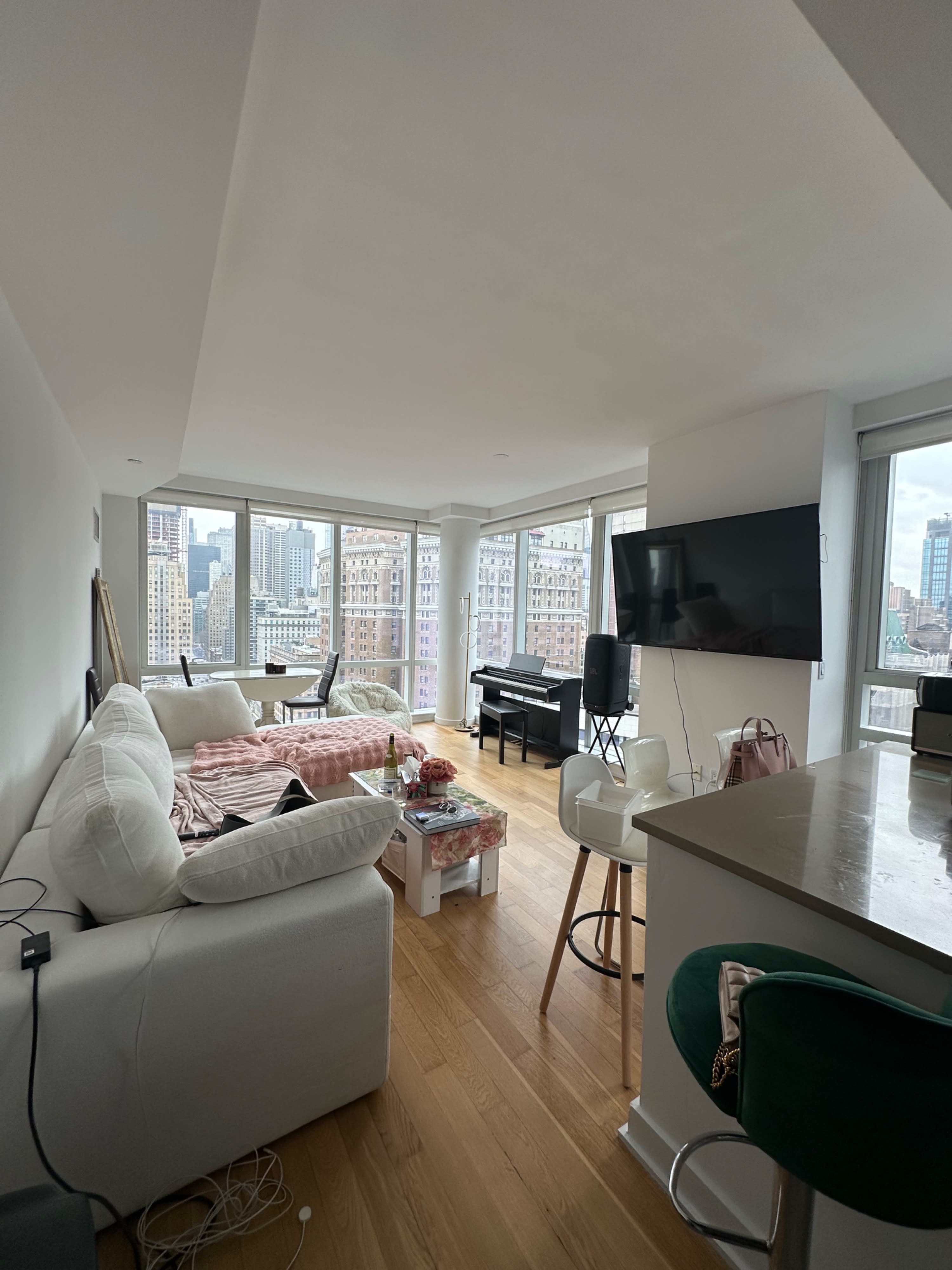 A film crew sets up equipment and prepares to shoot a scene in a bright, spacious apartment with a city view.