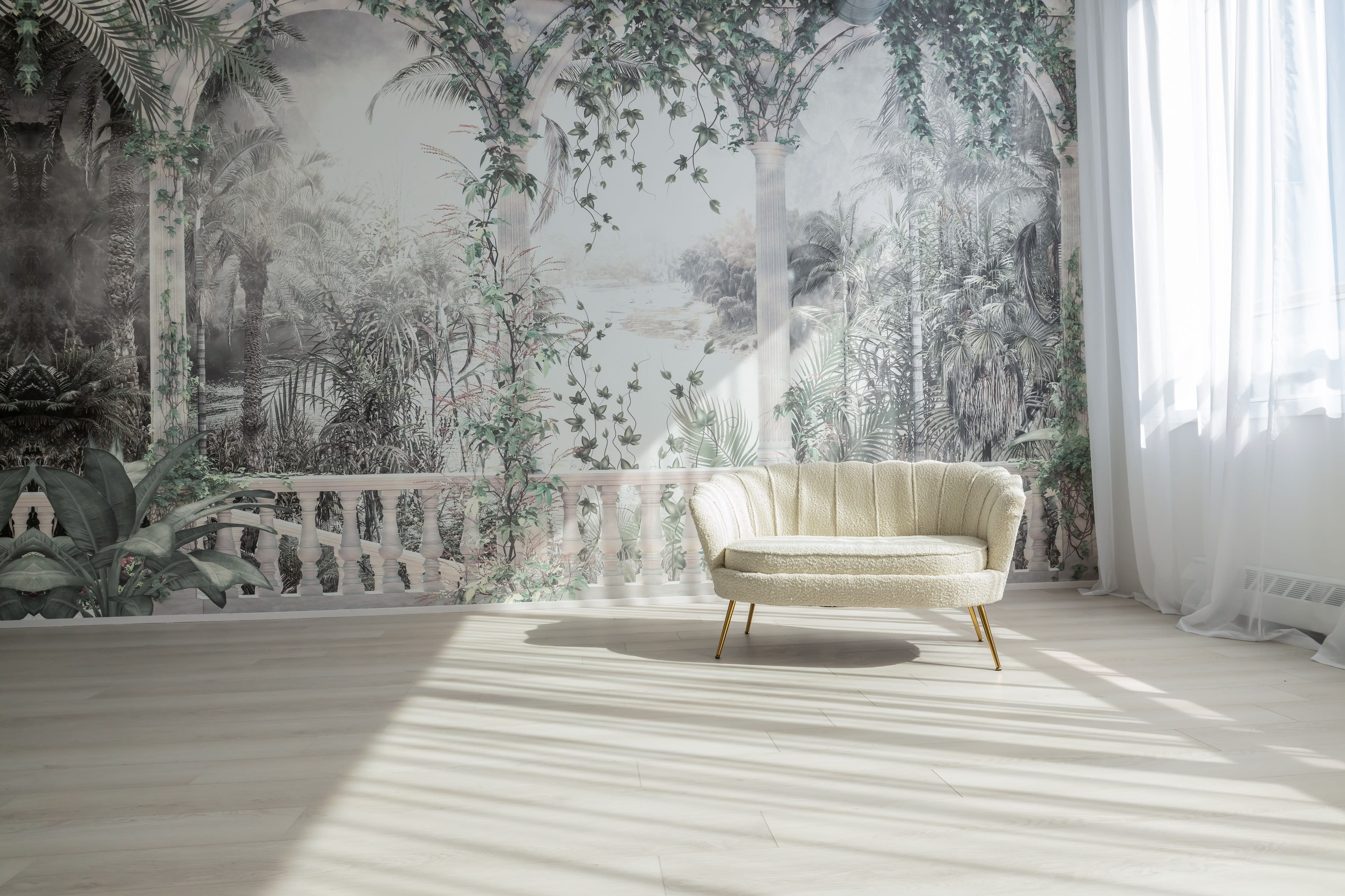 A decorated corner features a rattan chair, a round woven rug, a pouf, and decorative dried plants against a softly colored backdrop.
