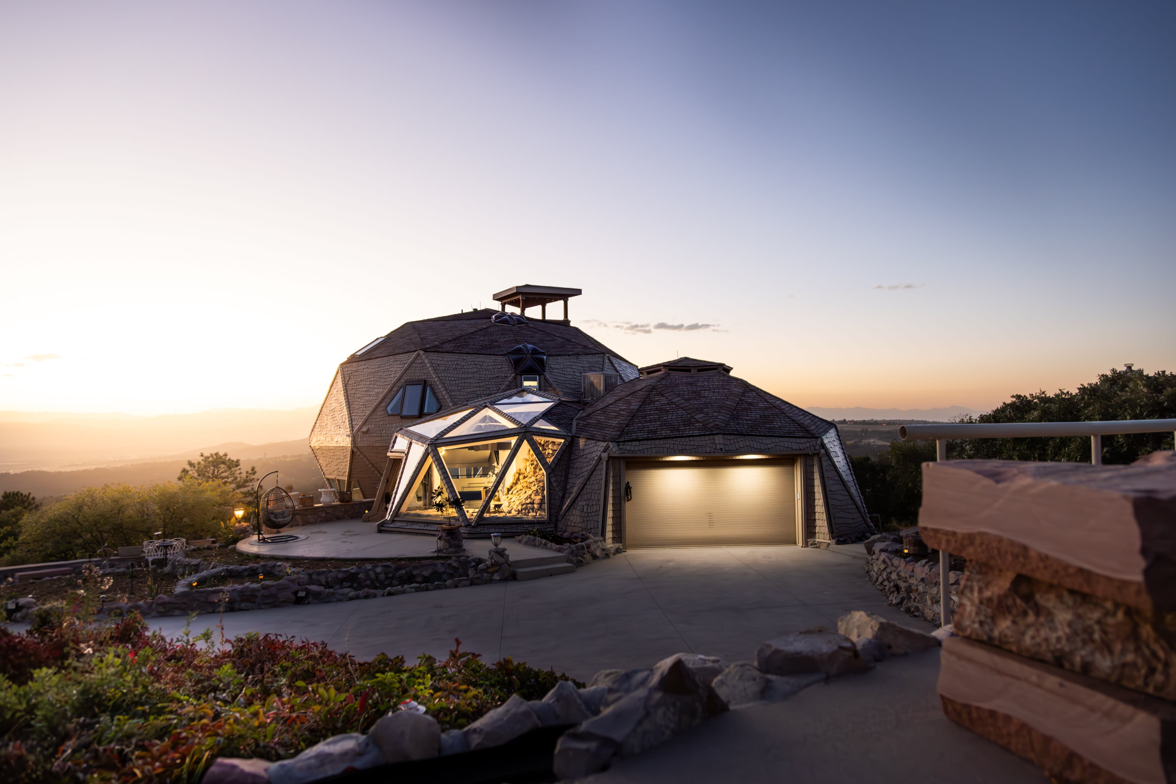 A birthday party is being held at a uniquely designed geodesic dome house with large windows and a stone base.