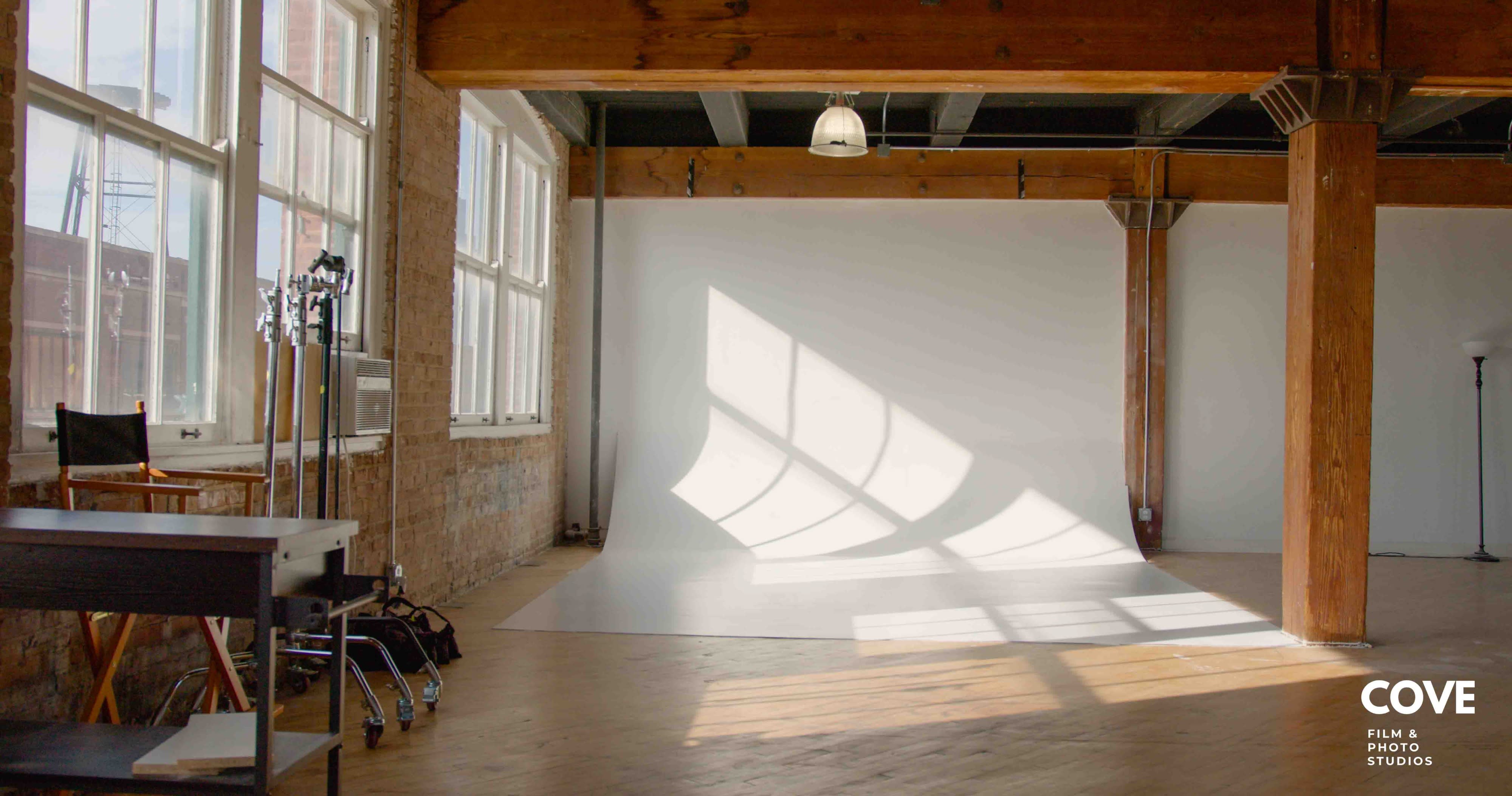 A dancer performs energetically in a dance studio while a videographer captures the movements with a camera.