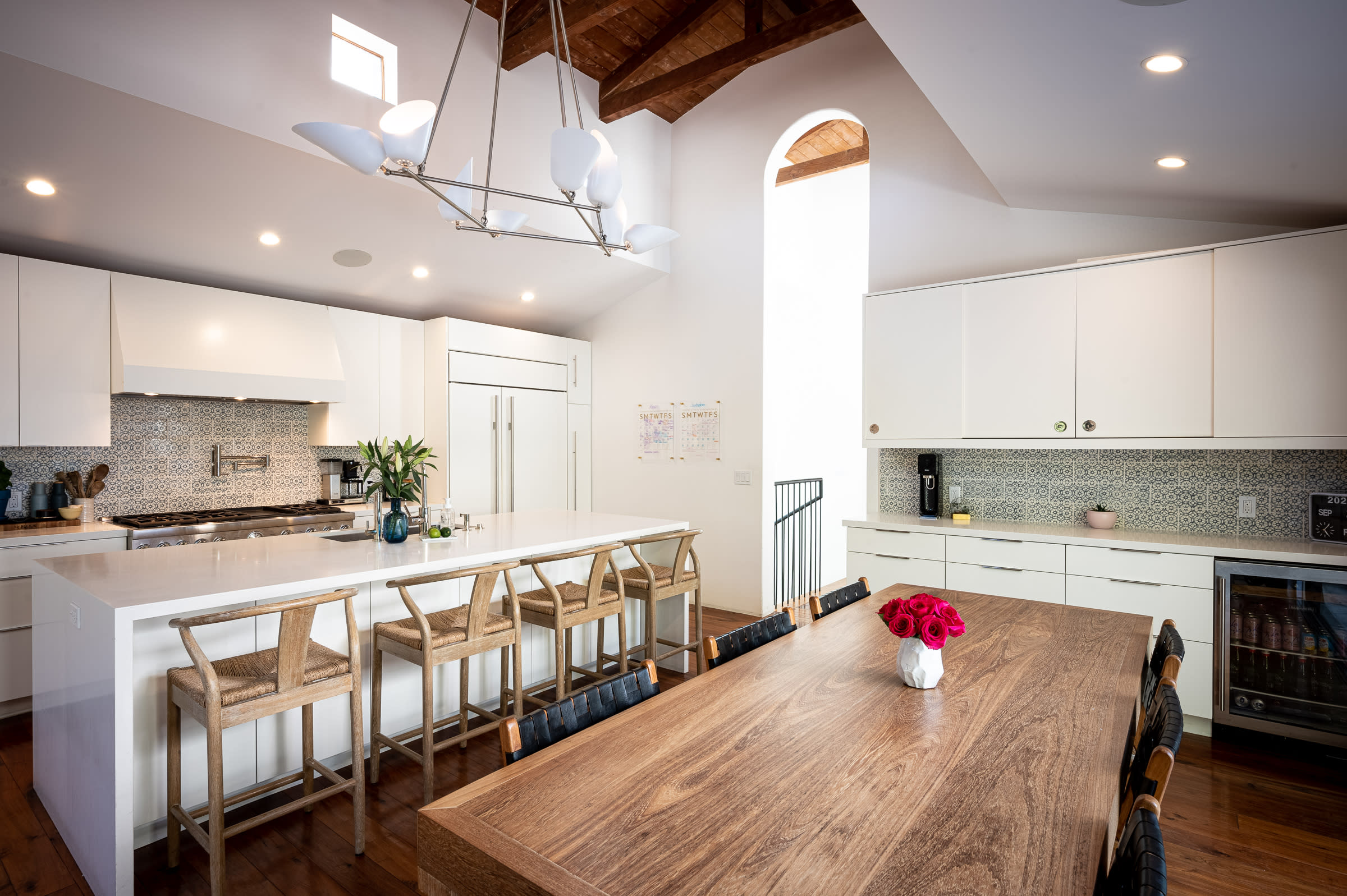A beautifully arranged dining table showcases an array of food platters, candles, and floral decorations in a modern kitchen setting.