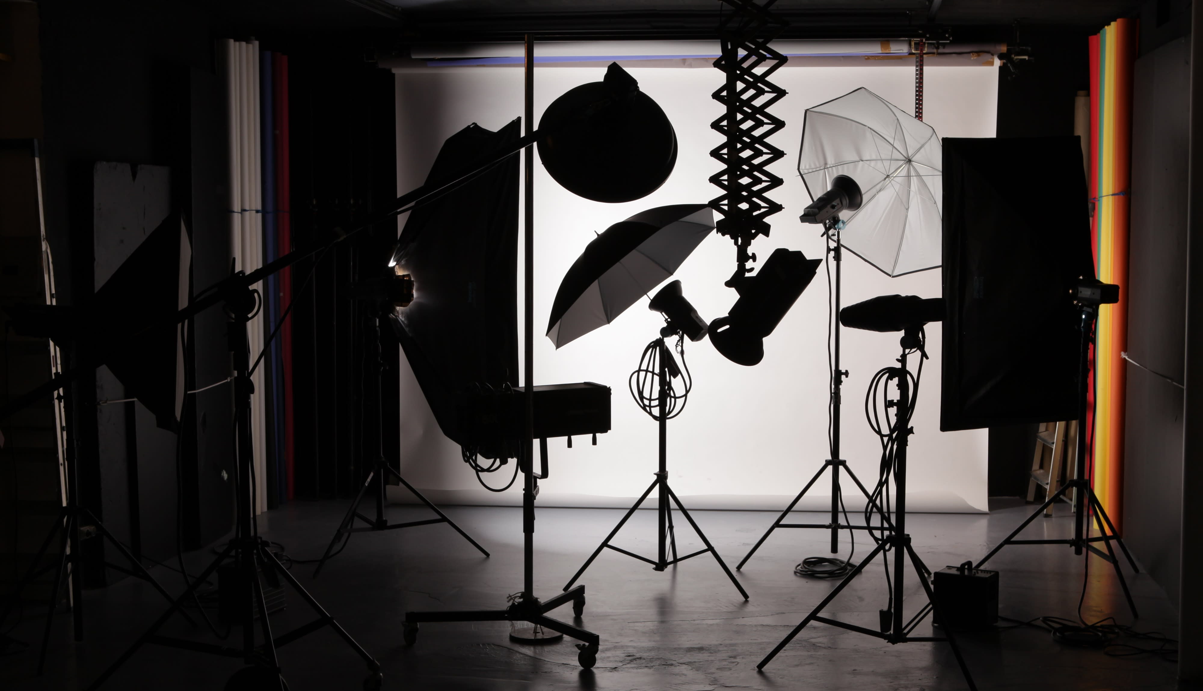 A singer performs against a bright backdrop during a video shoot, surrounded by studio lighting and equipment.