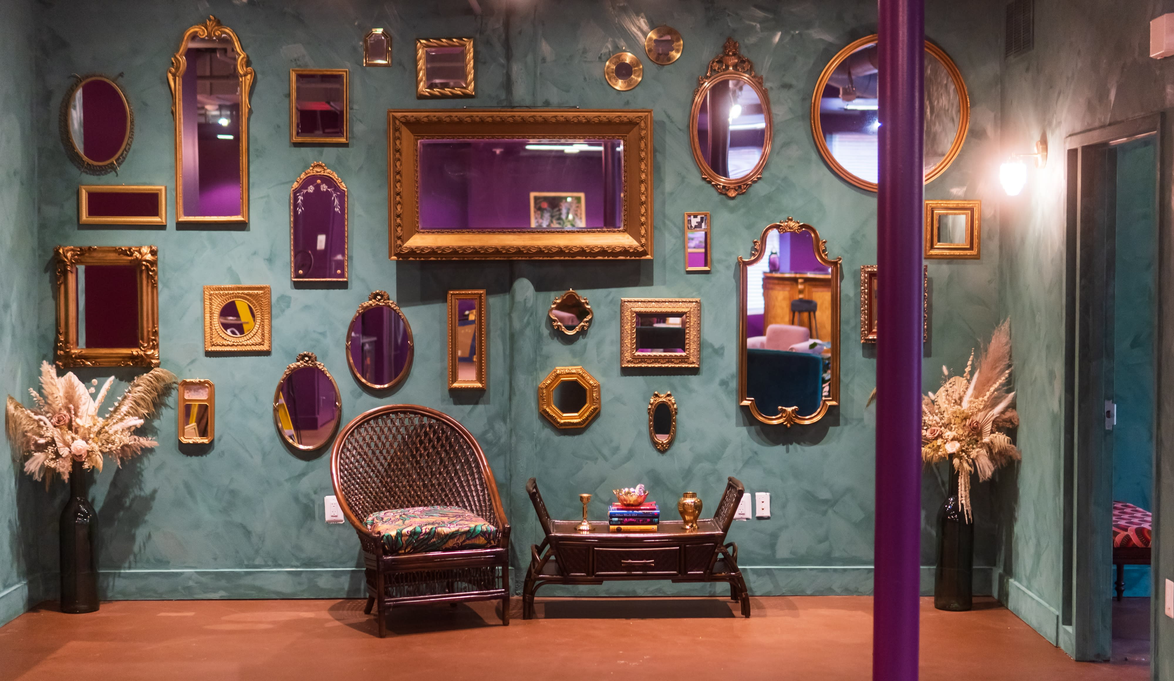 A model poses confidently in a stylish outfit against a backdrop of ornate mirrors on a purple wall.