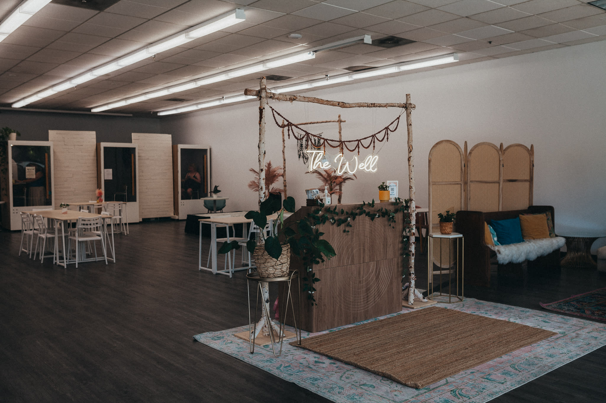 People gather in a spacious room filled with tables as they celebrate a life event, engaging in conversation and enjoying the decorations and floral arrangements.