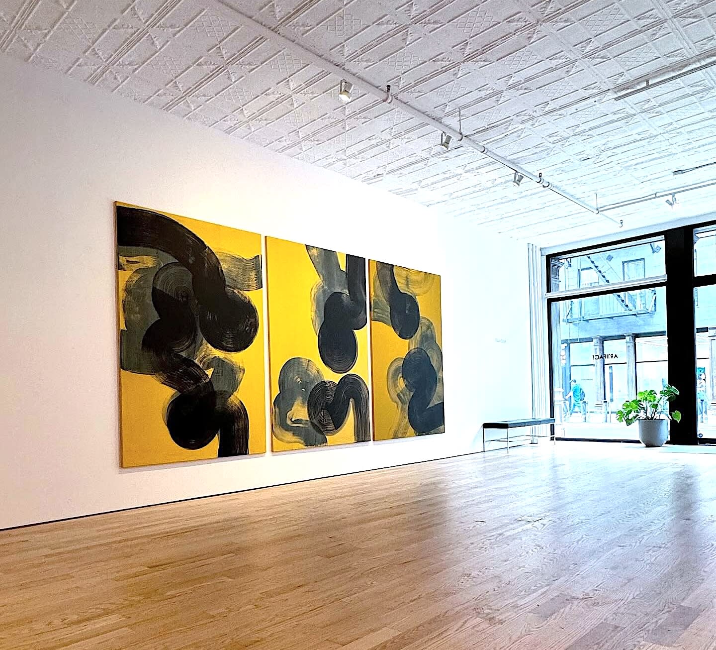 Two women engage in conversation while attending an art exhibit in a gallery filled with visitors.