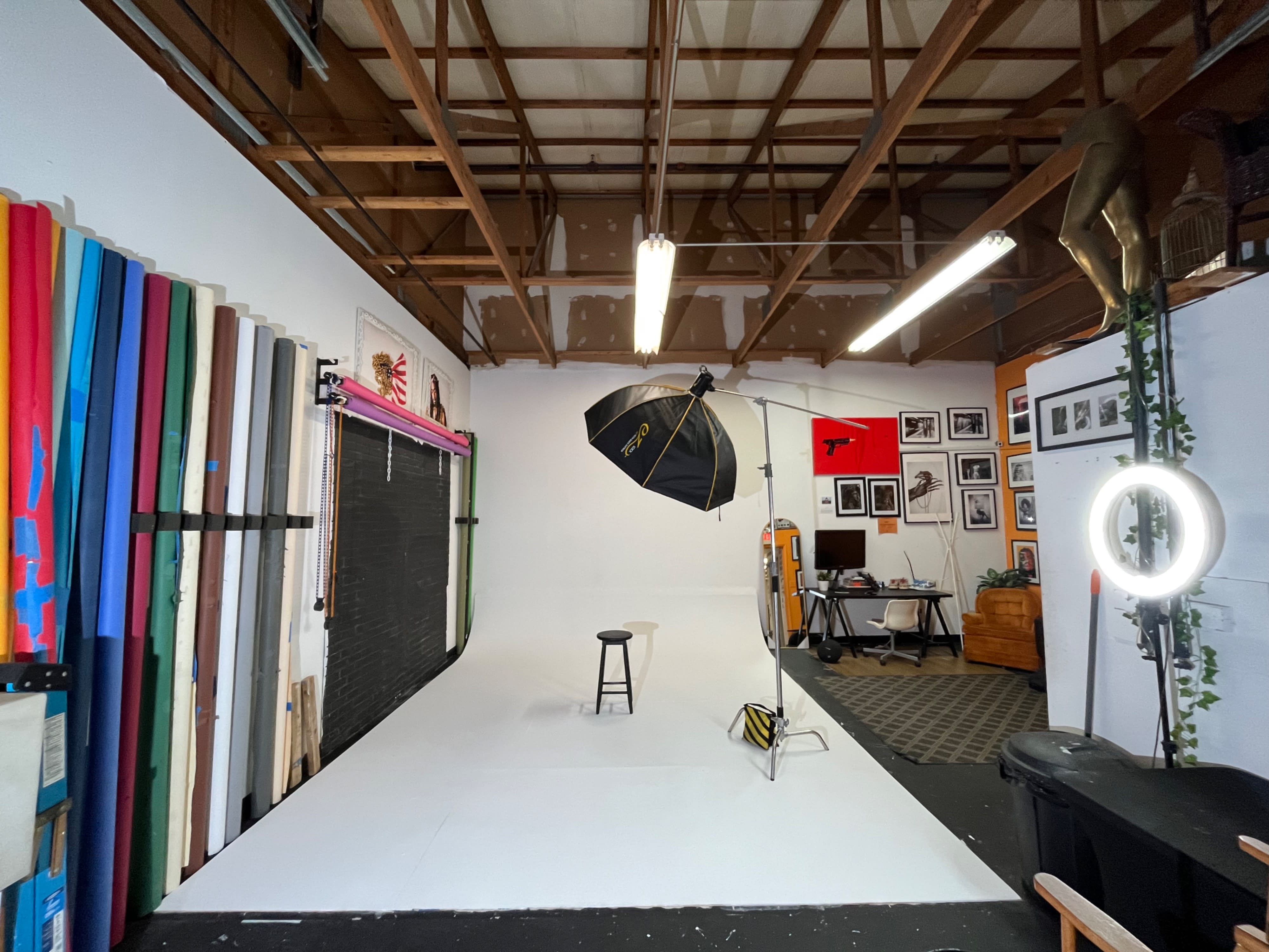A model sits on the floor in front of a neutral backdrop while a photographer prepares to take pictures.