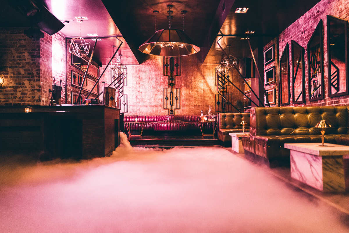 A photographer captures an image of a model dressed in a costume against the backdrop of a stylish bar.