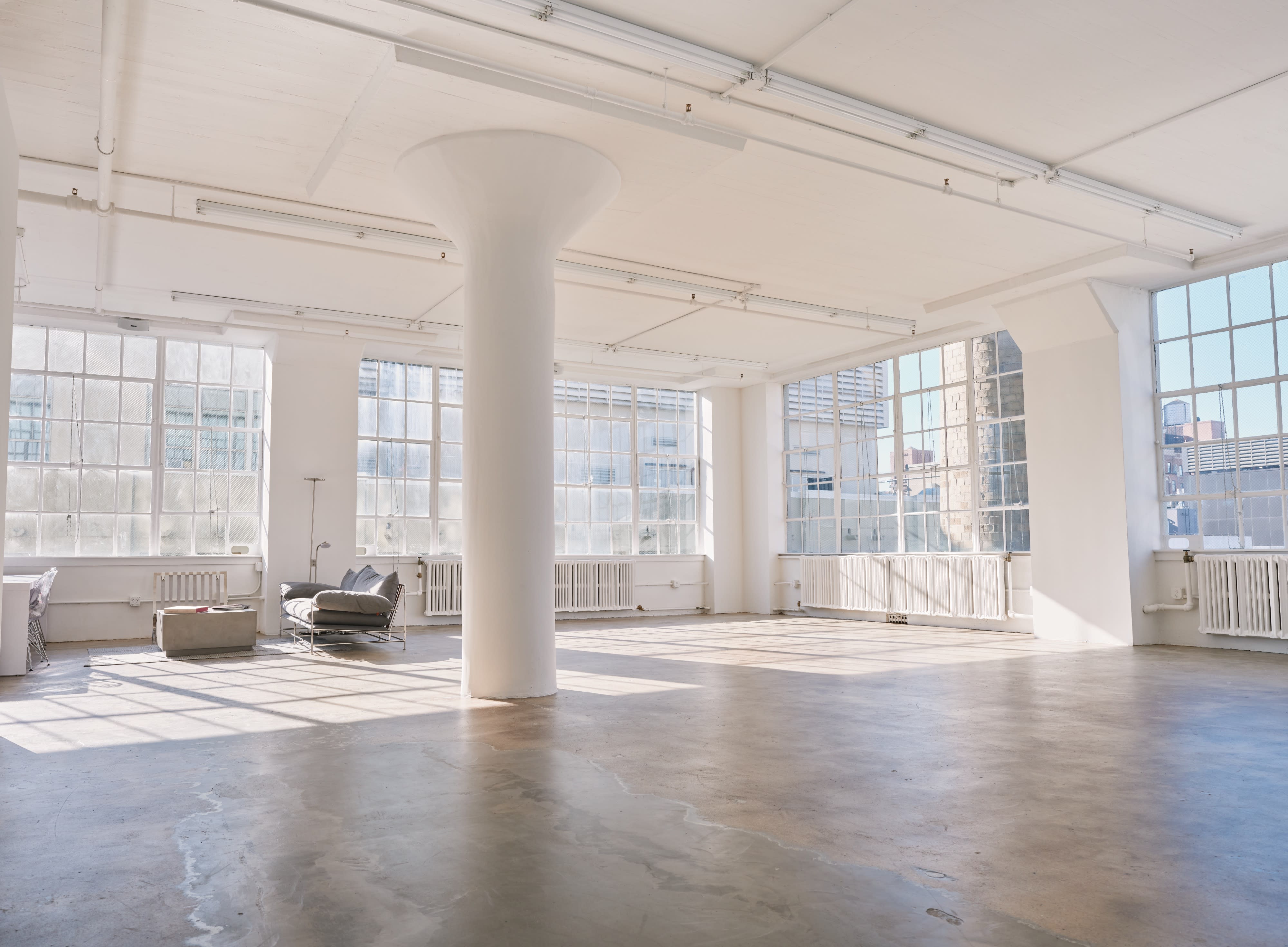 A musician plays a harp in a spacious, sunlit room with large windows.