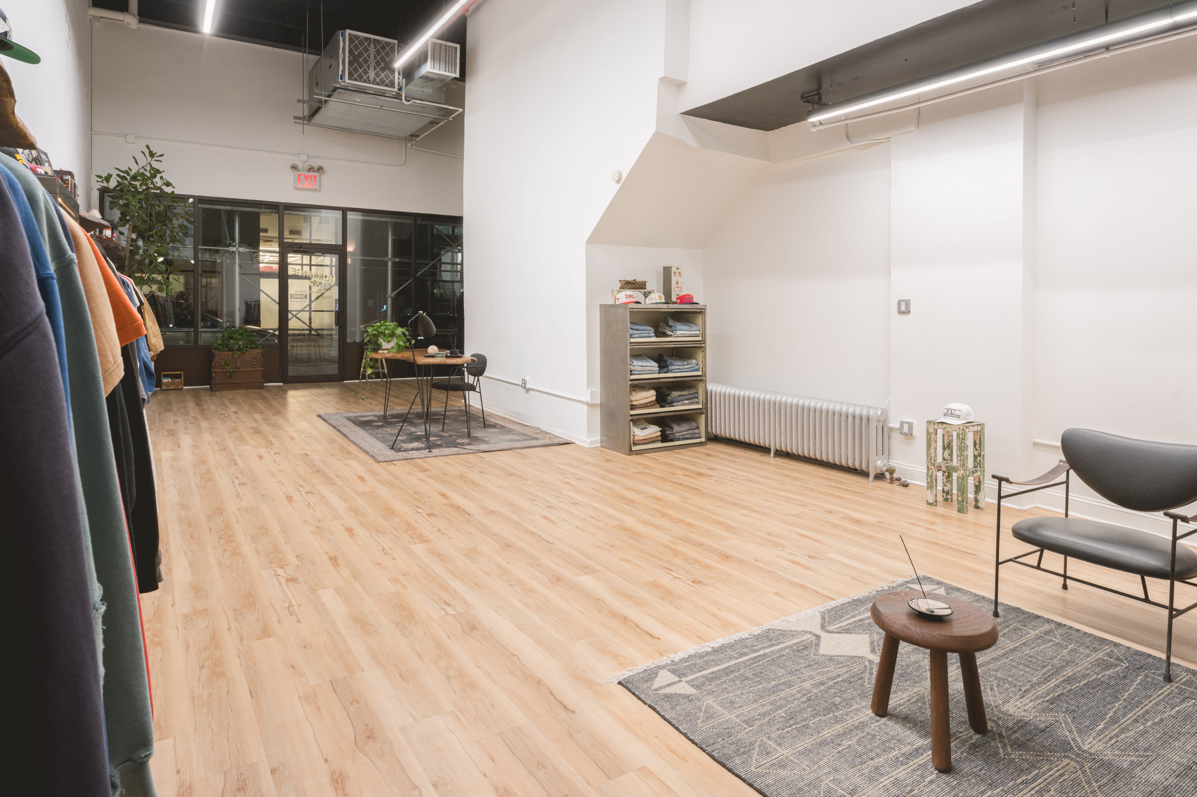 A pop-up shop features a spacious layout with denim clothing displayed on racks, a bench, and a trunk in the center.