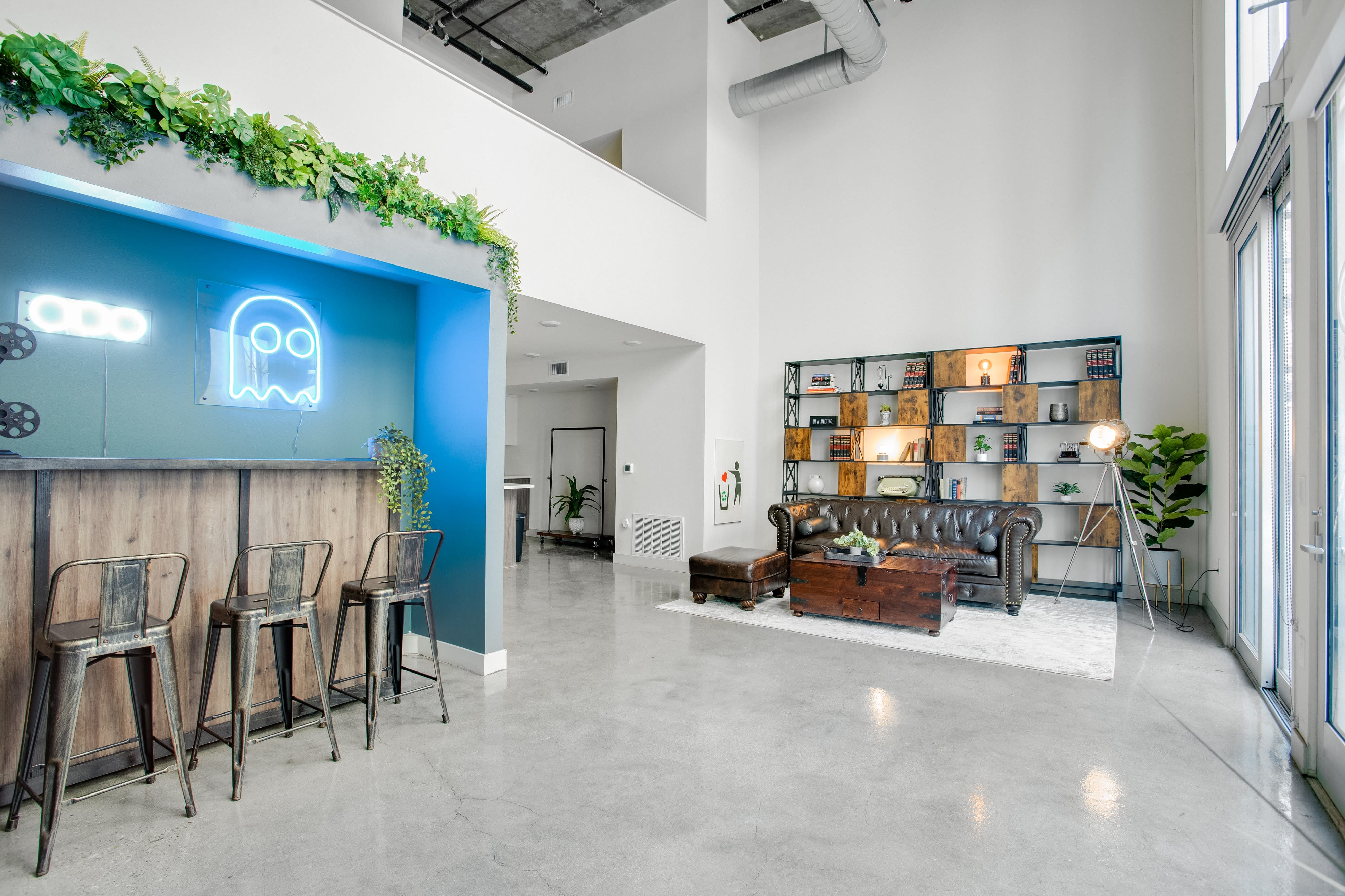 A video shoot is taking place in a modern living room featuring a leather couch, a wooden coffee table, and a bookshelf filled with books and decorative items.