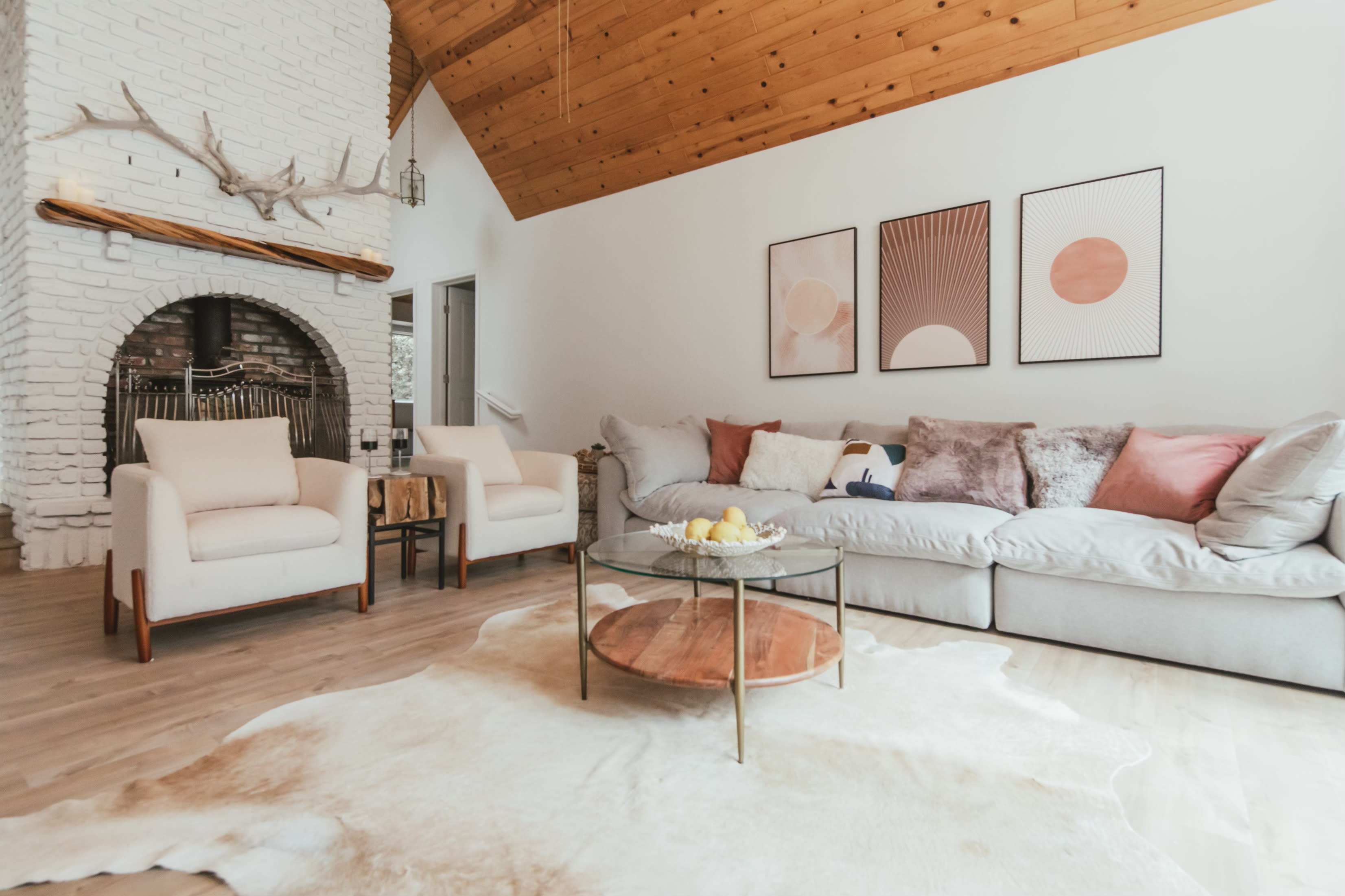 A cozy living room features a fireplace with festive stockings, a decorated Christmas tree, and neatly wrapped gifts under it.