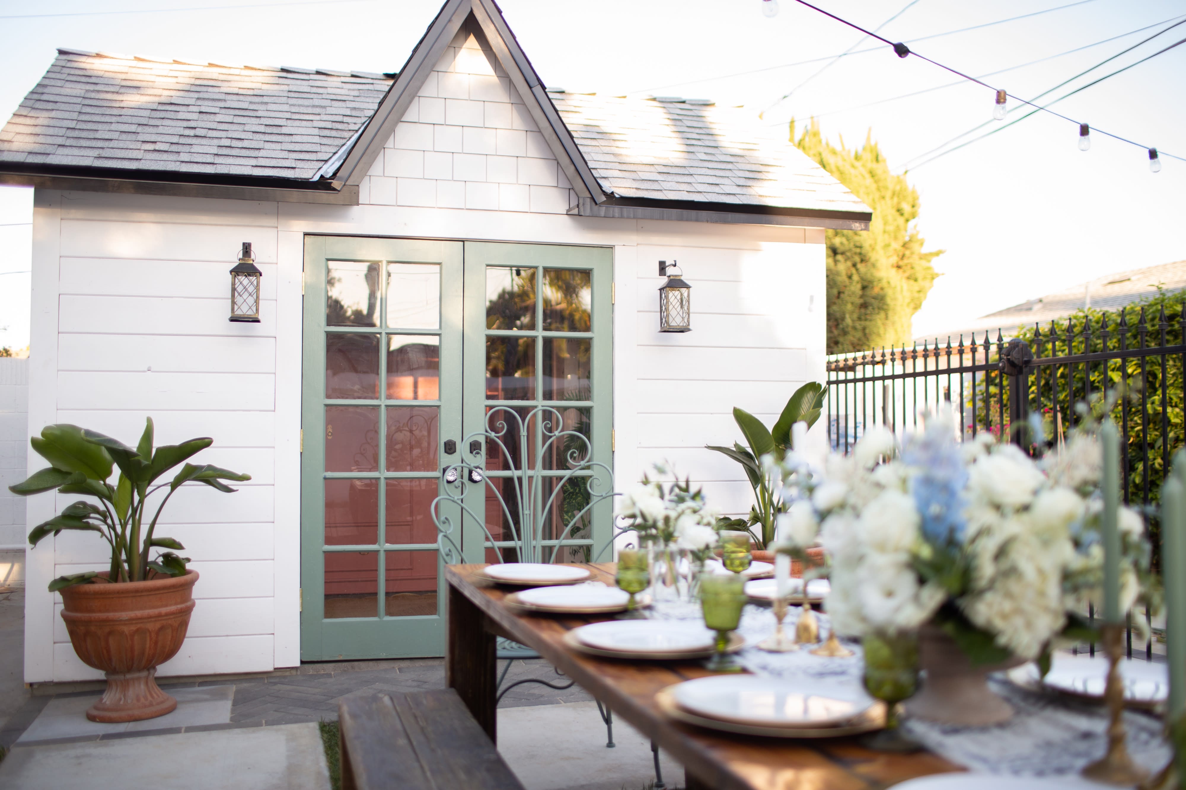 Guests at a bridal shower are seated at tables, painting canvases and enjoying a creative activity outdoors.