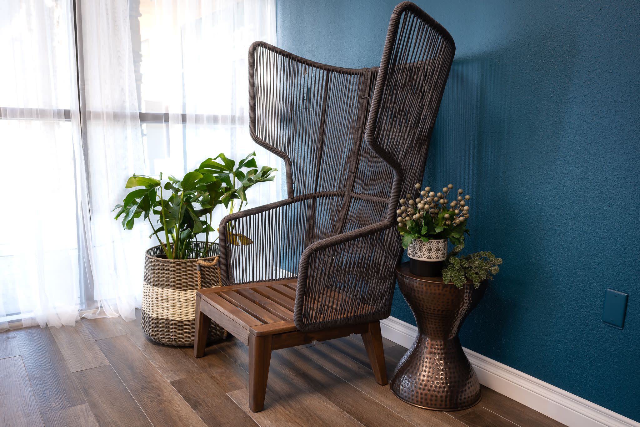 A model poses on a chaise lounge against a dark blue wall adorned with decorative frames.