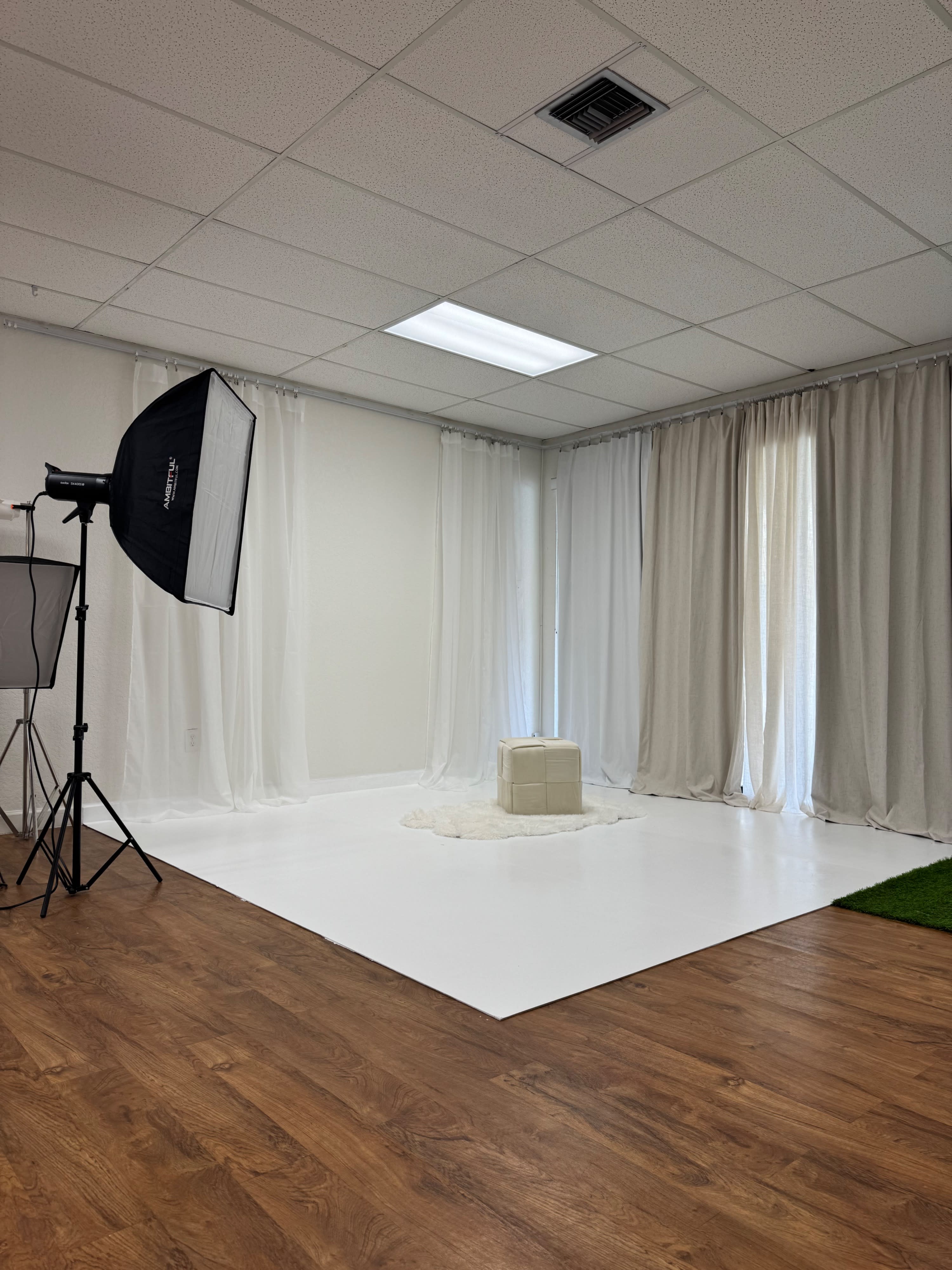 A person poses on a stool against a white backdrop during a photo shoot.