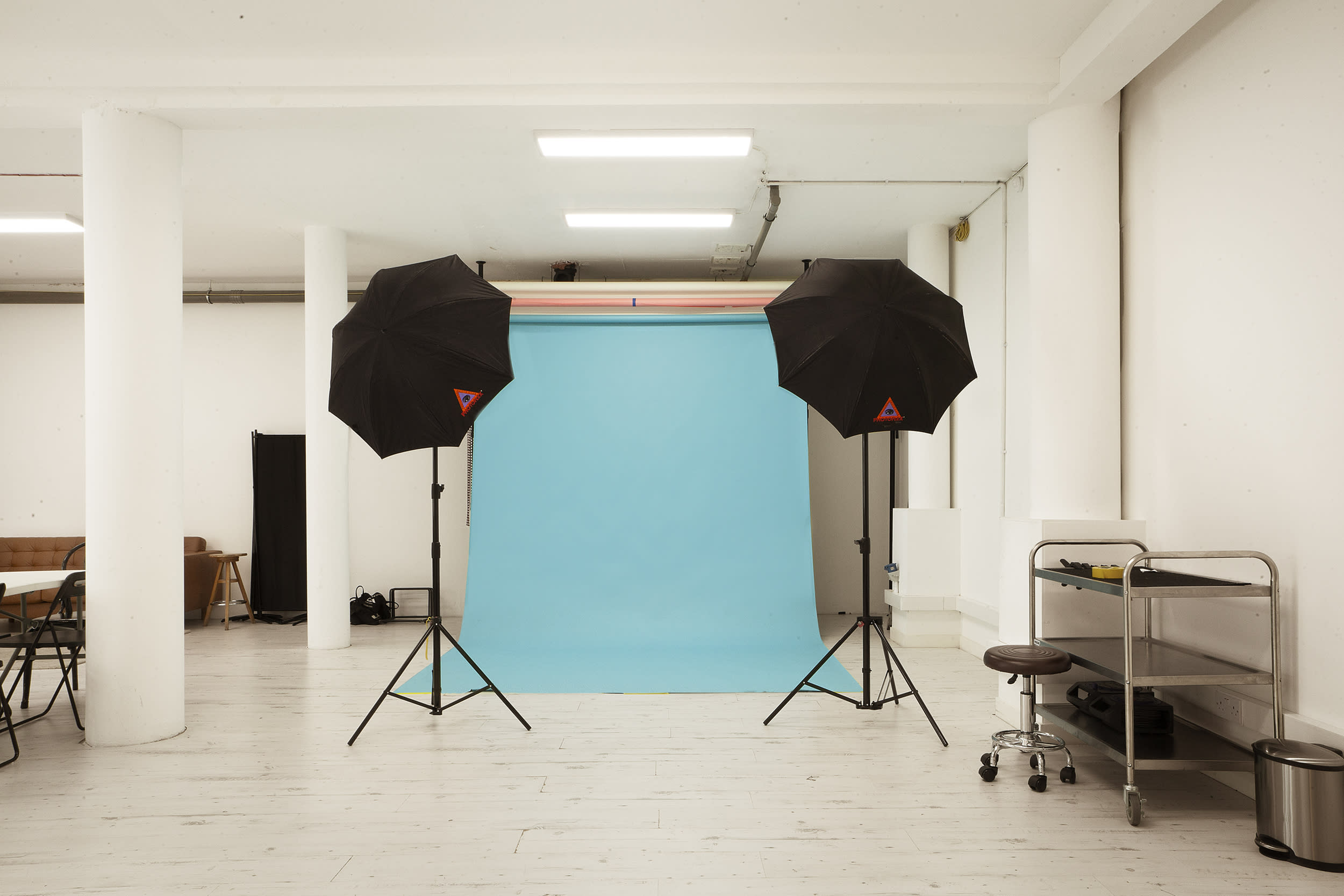 A photographer captures a model in a wetsuit against a white backdrop during a photo shoot.