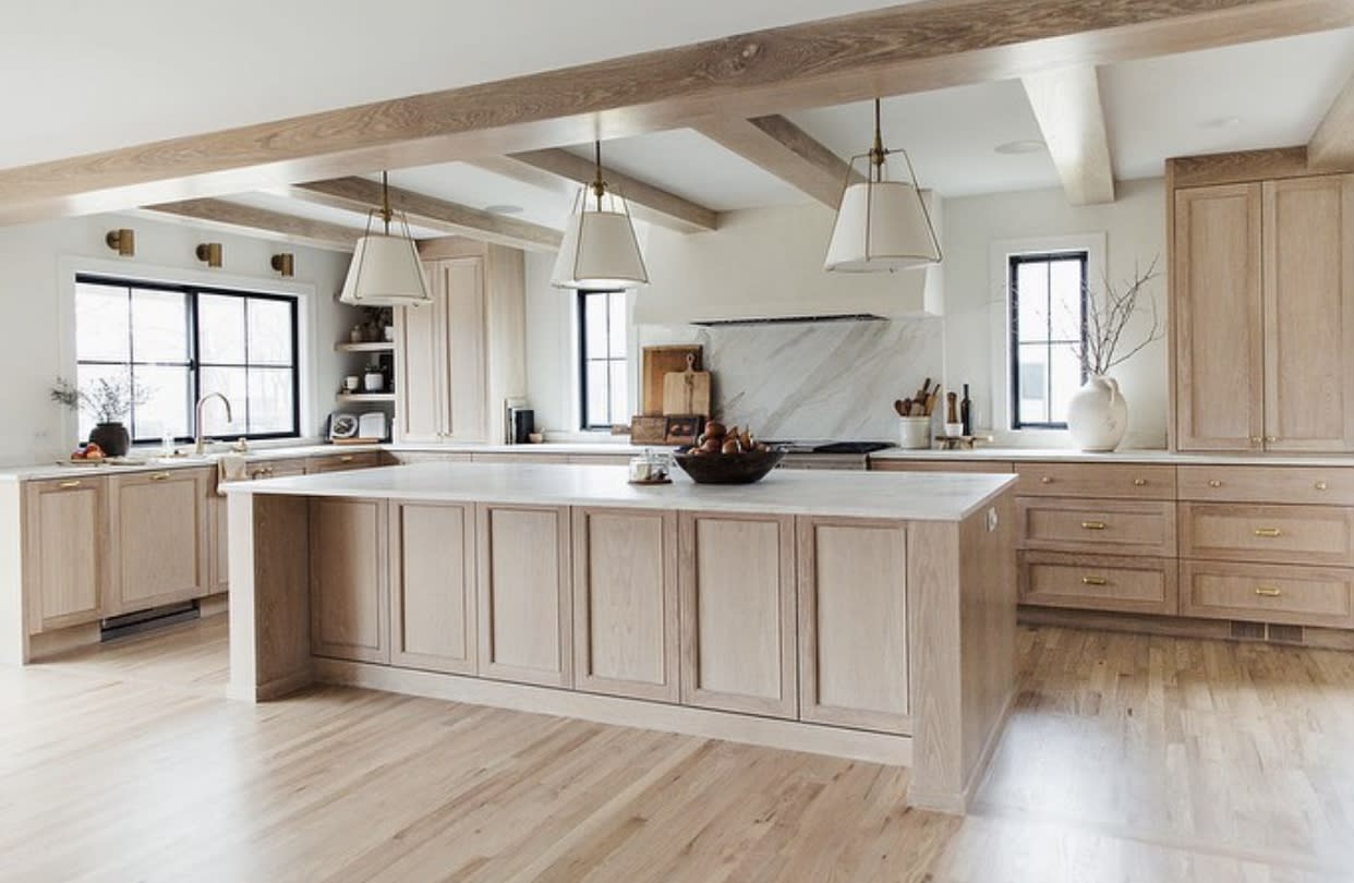 A woman stands confidently at a kitchen island, looking thoughtfully into the distance.