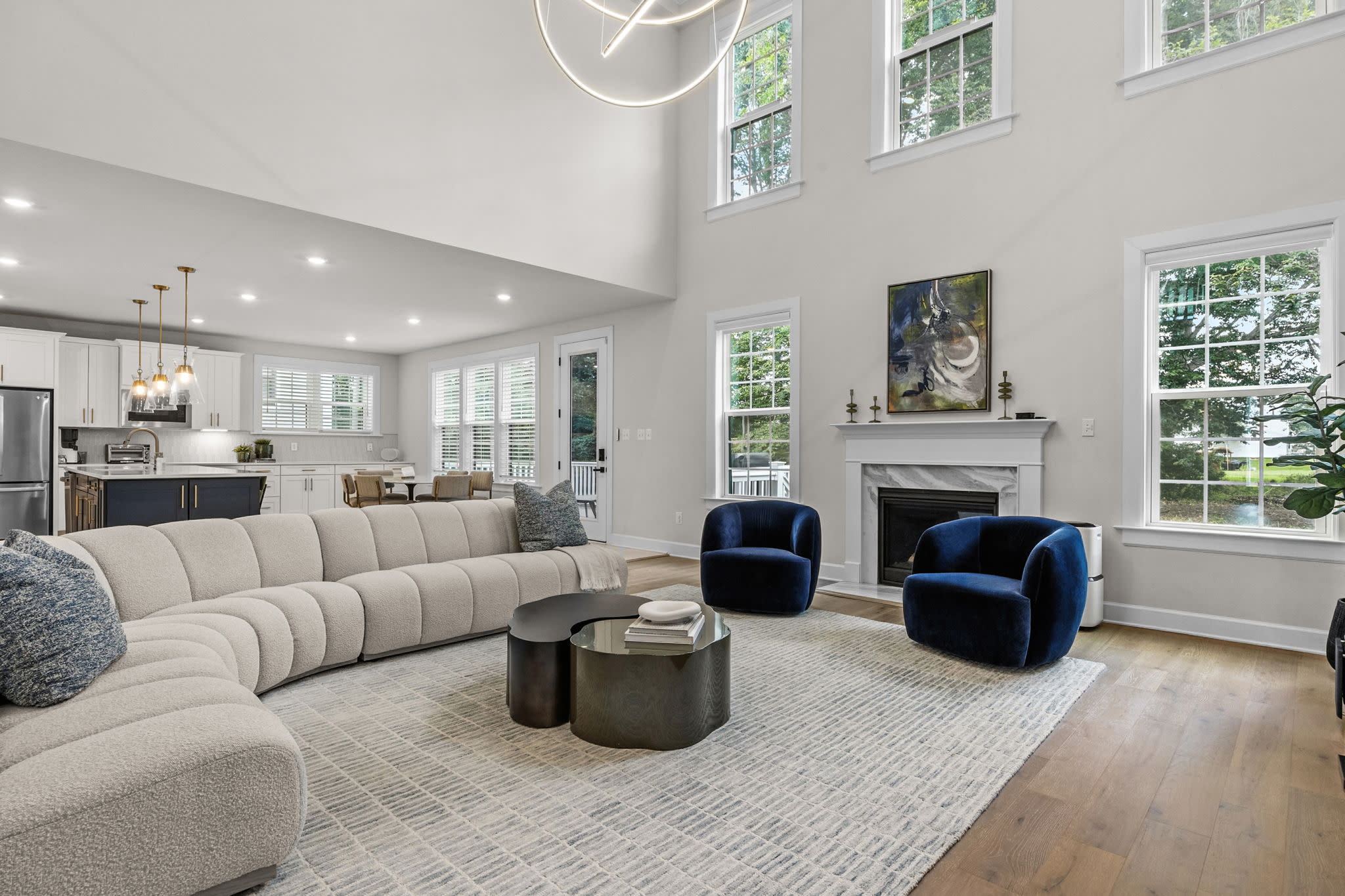 Guests are gathered in a modern living room, sitting on a couch and focused on their smartphones, likely anticipating the reveal at the gender reveal party.