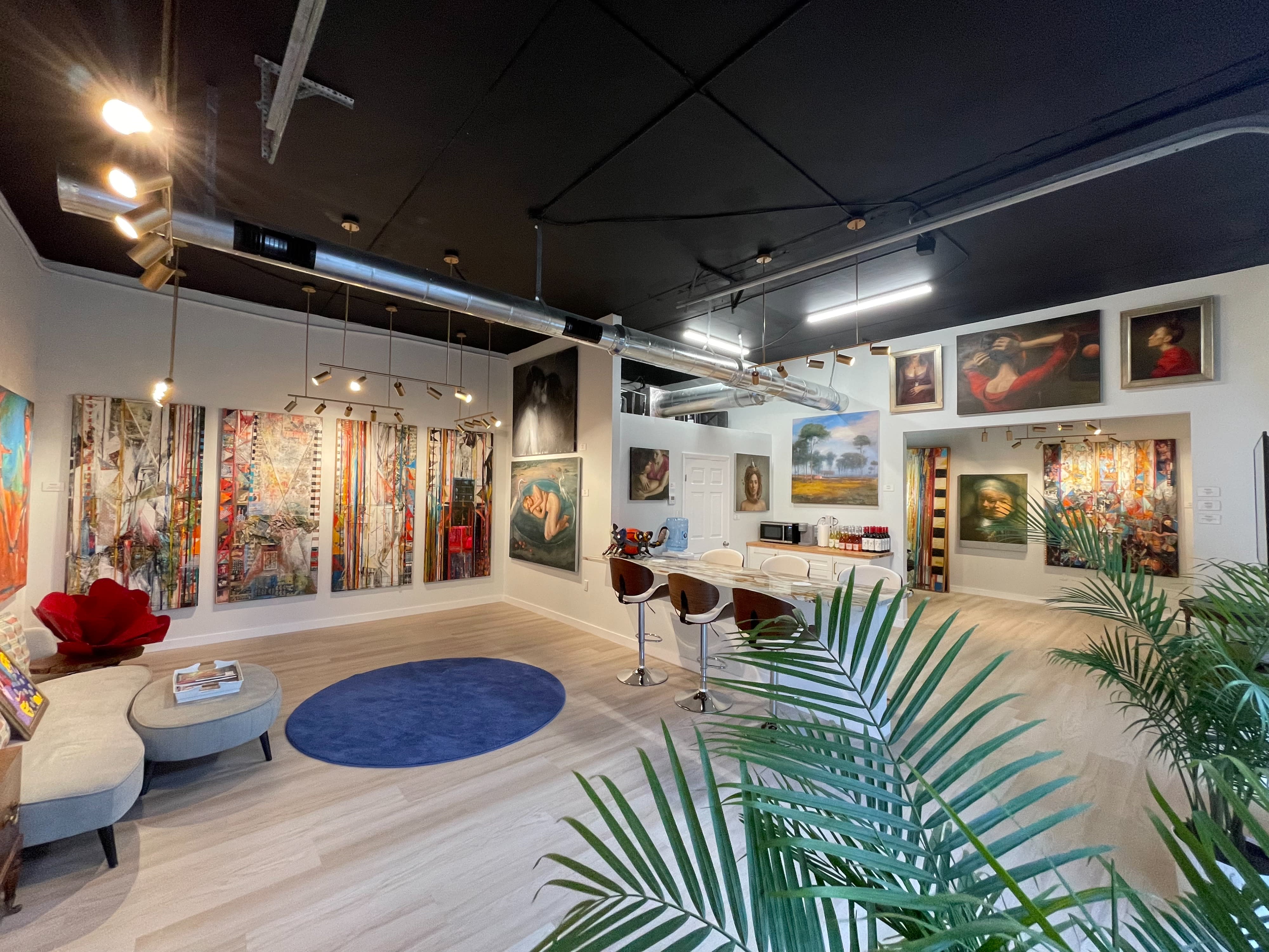 A group of people celebrates a graduation party in a vibrant venue decorated with artwork, enjoying food and drinks at elegantly set tables.