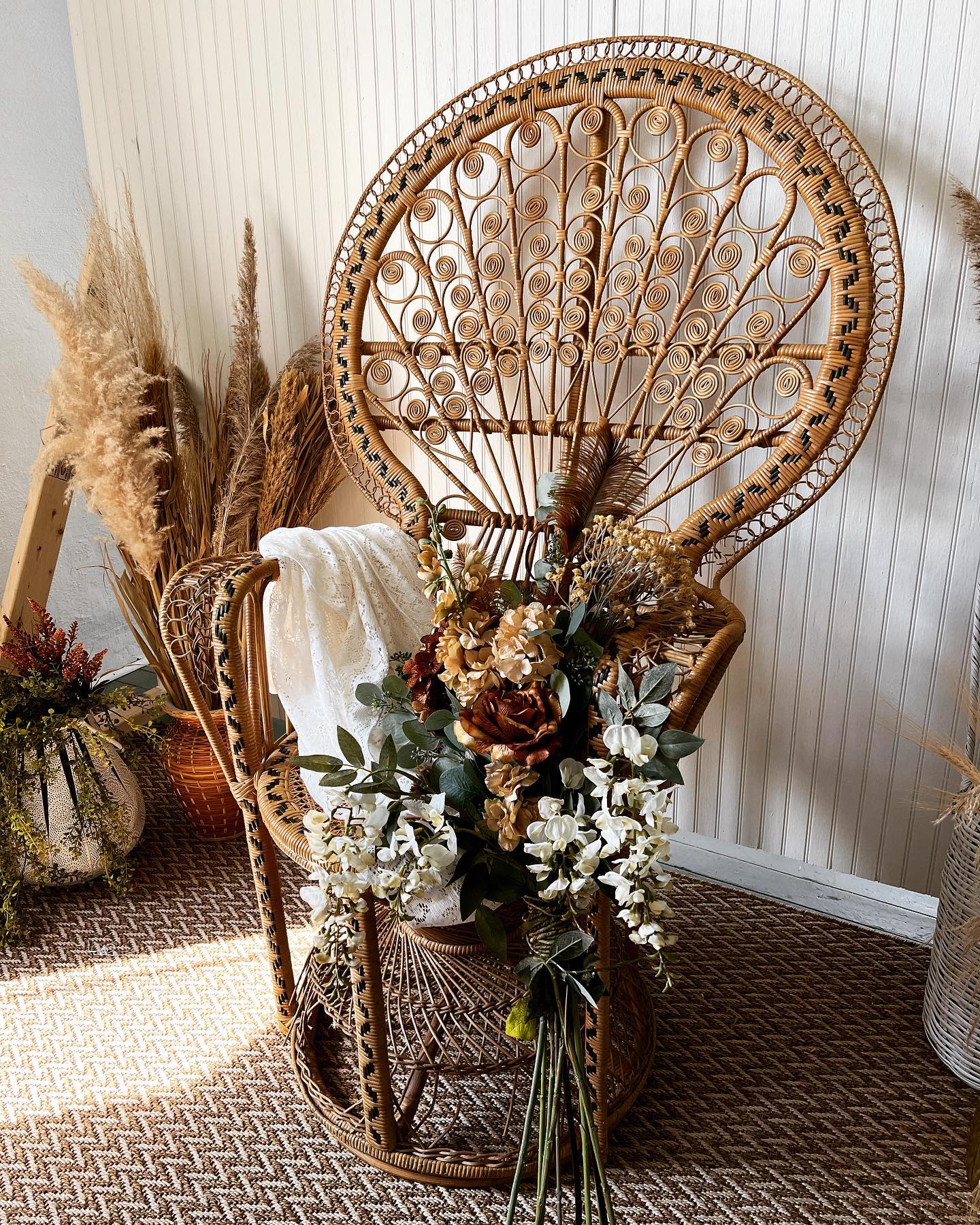 A bride stands by a window, draping her veil over her head in a softly lit room.