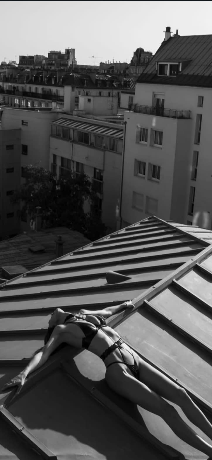 A person sits on a rooftop ledge, looking contemplatively at the city skyline.