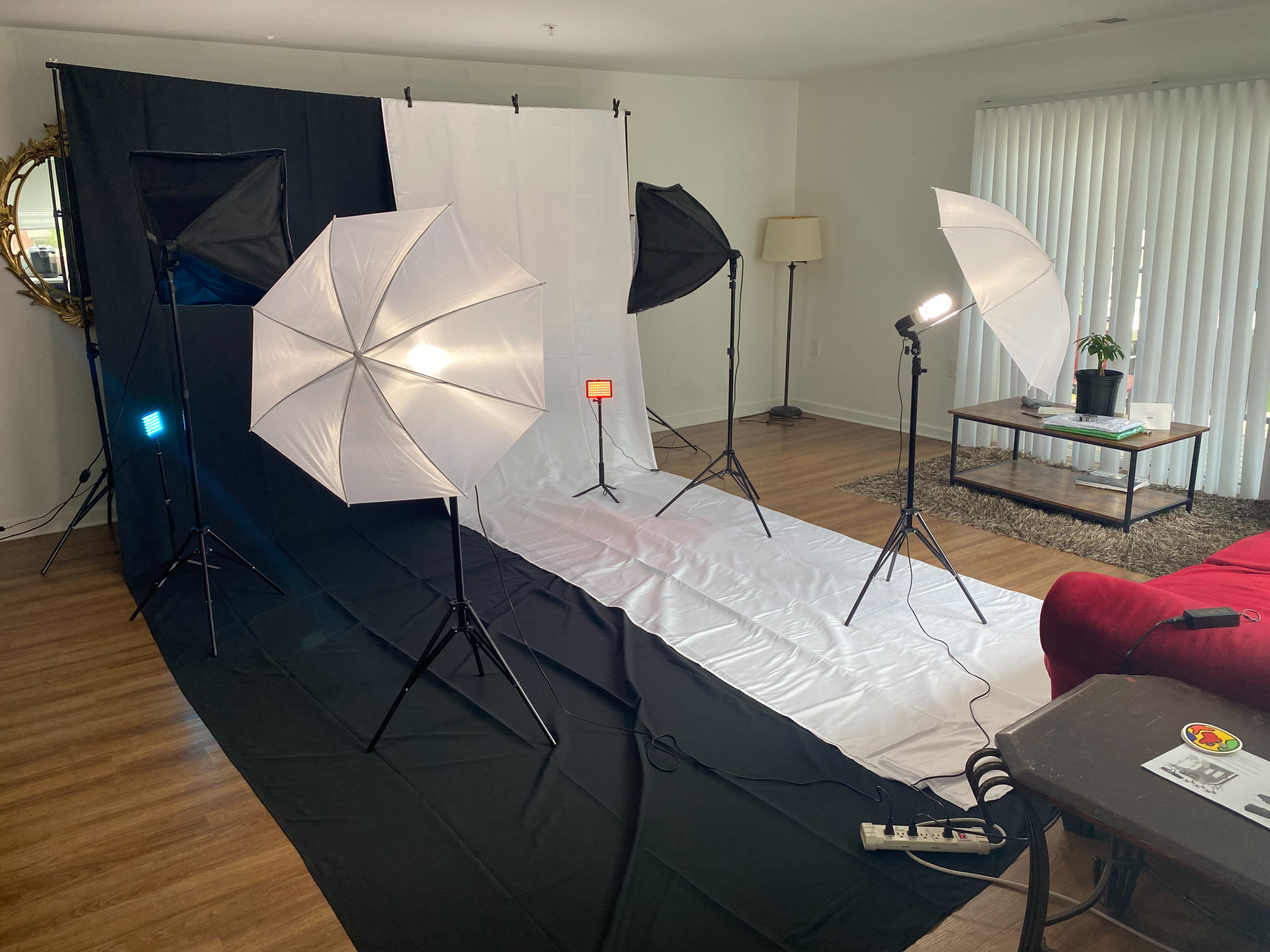 A model poses confidently in front of a camera while a photographer adjusts lighting equipment during a photoshoot.
