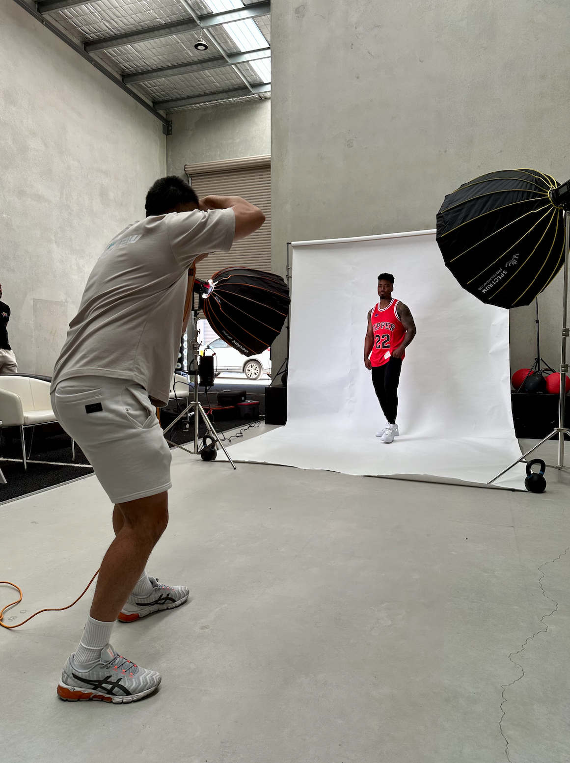 Two models pose on a chair for a photo shoot, showcasing casual streetwear outfits.