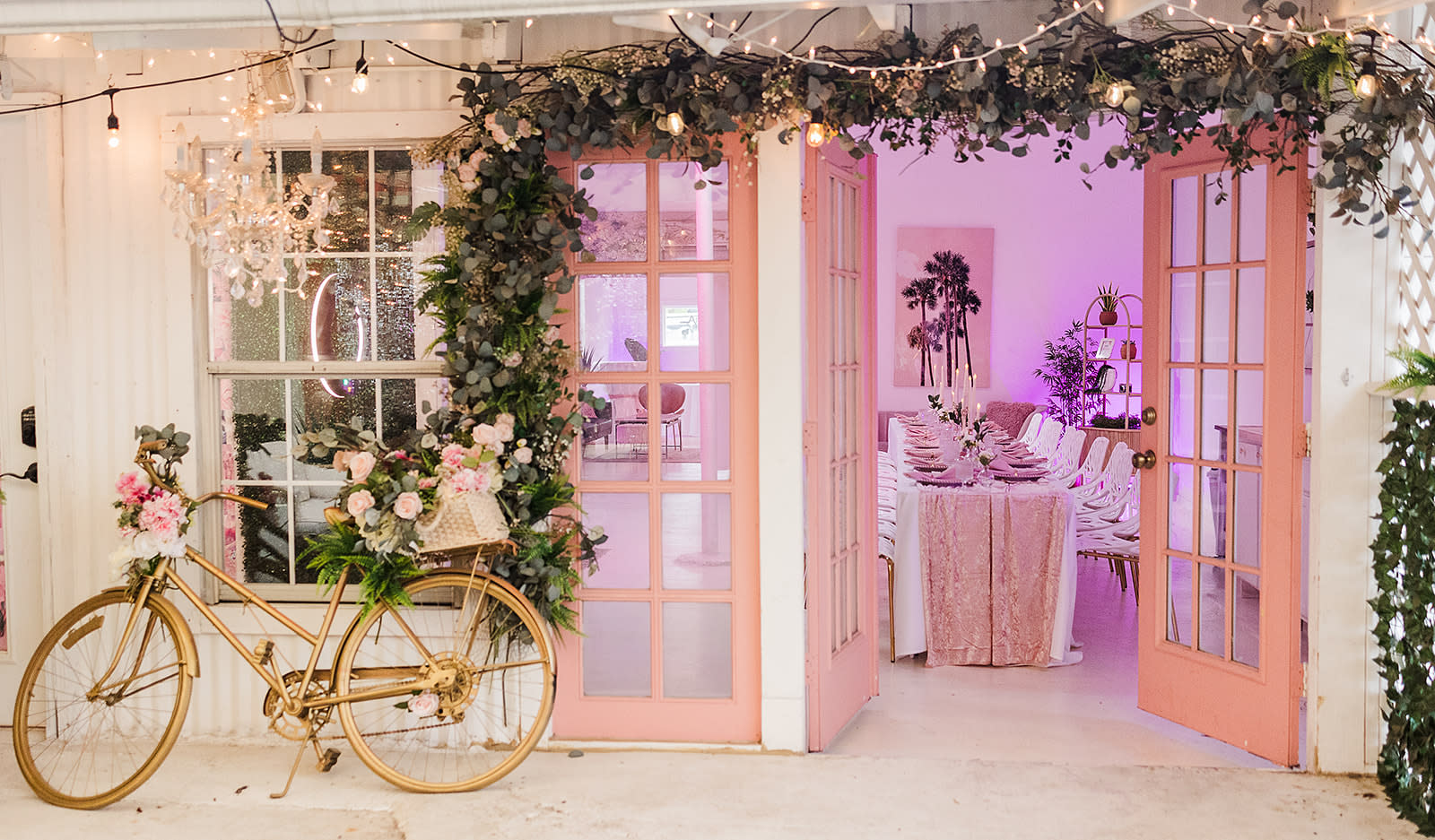A decorative backdrop featuring a floral arrangement and a baby carriage adorned with flowers marks a baby shower celebration.