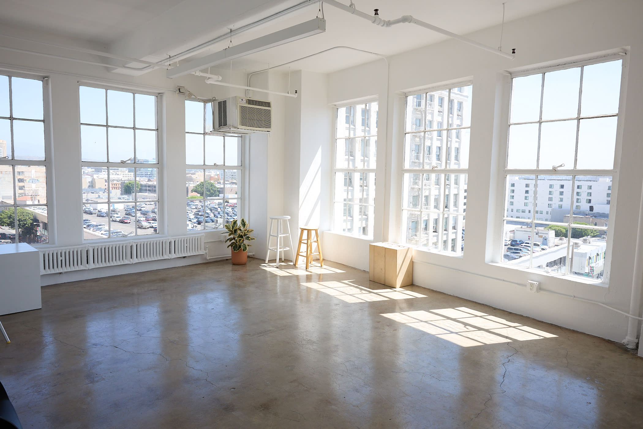 A photographer is setting up a camera to capture a photo shoot featuring clothing on racks in a minimalist studio space.