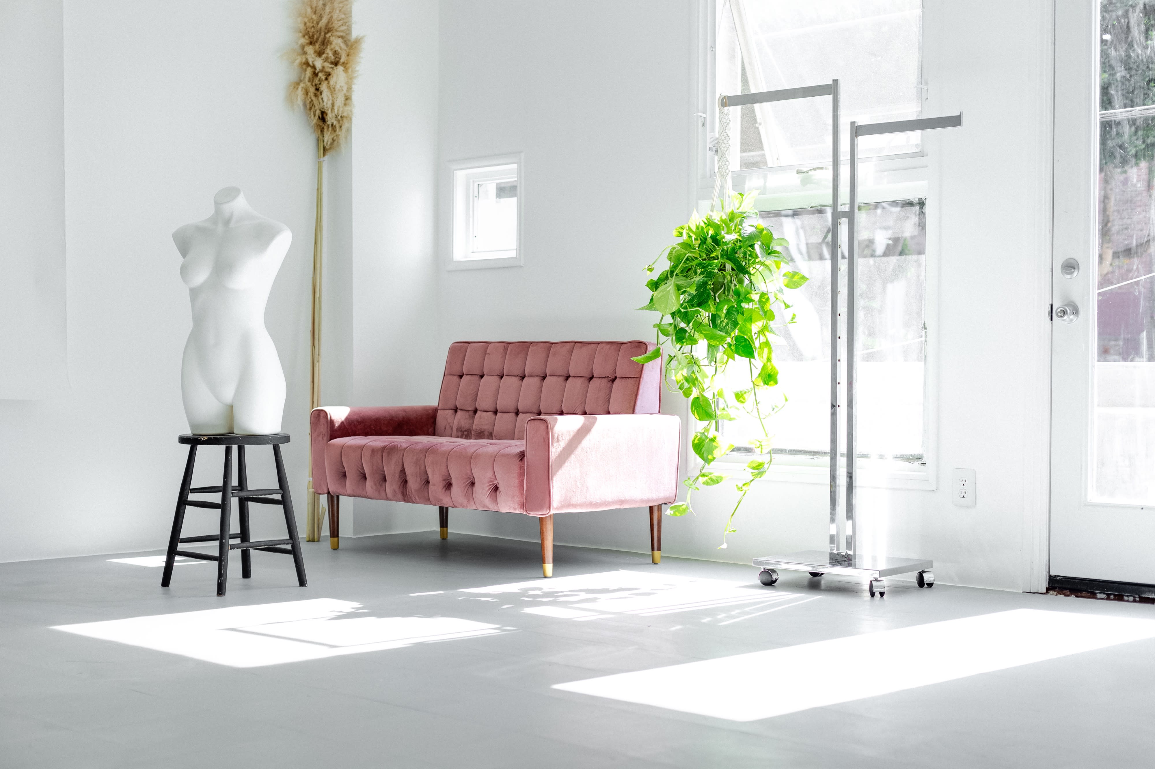 A model poses on the floor of a bright, minimalist room while drinking from a glass.