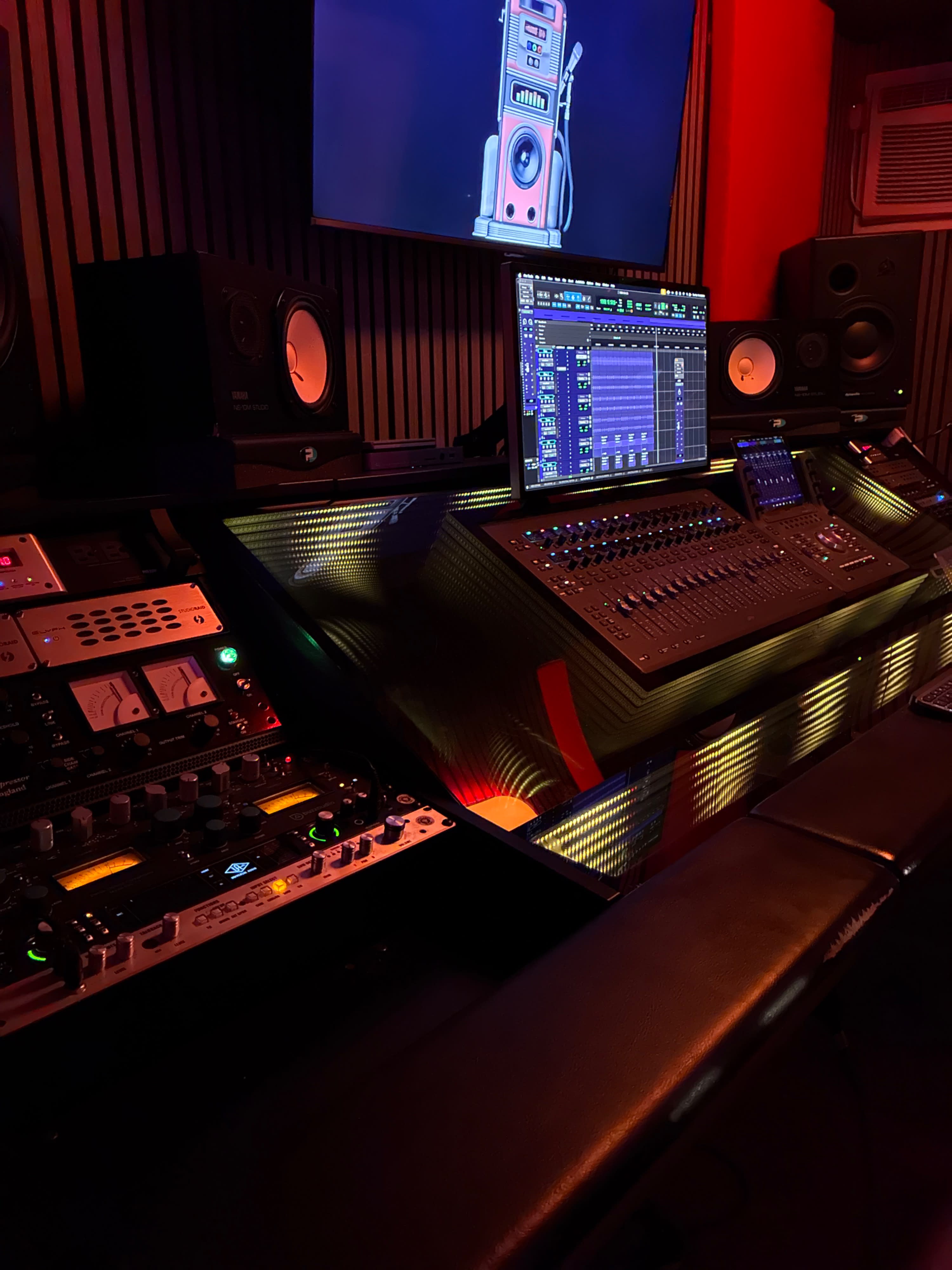 Two individuals are working in a music studio, focusing on a soundboard while discussing recording techniques.