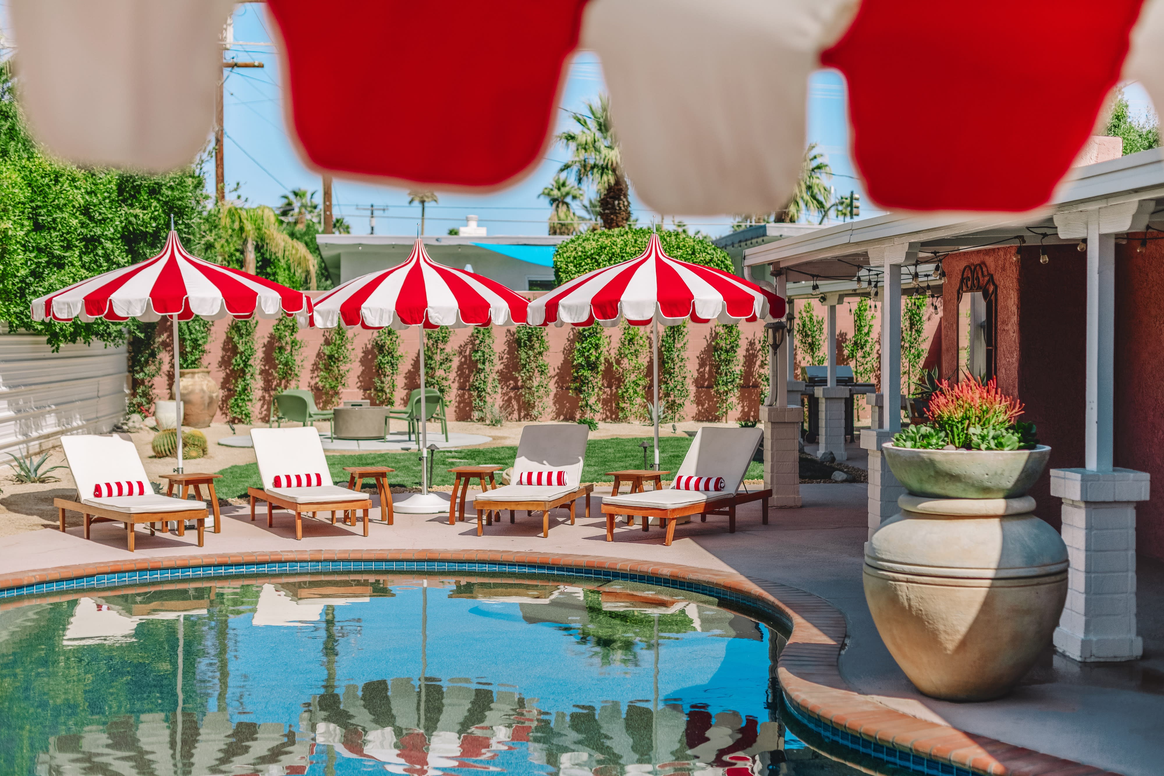 A model poses in a red dress by a poolside, showcasing a stylish summer look.