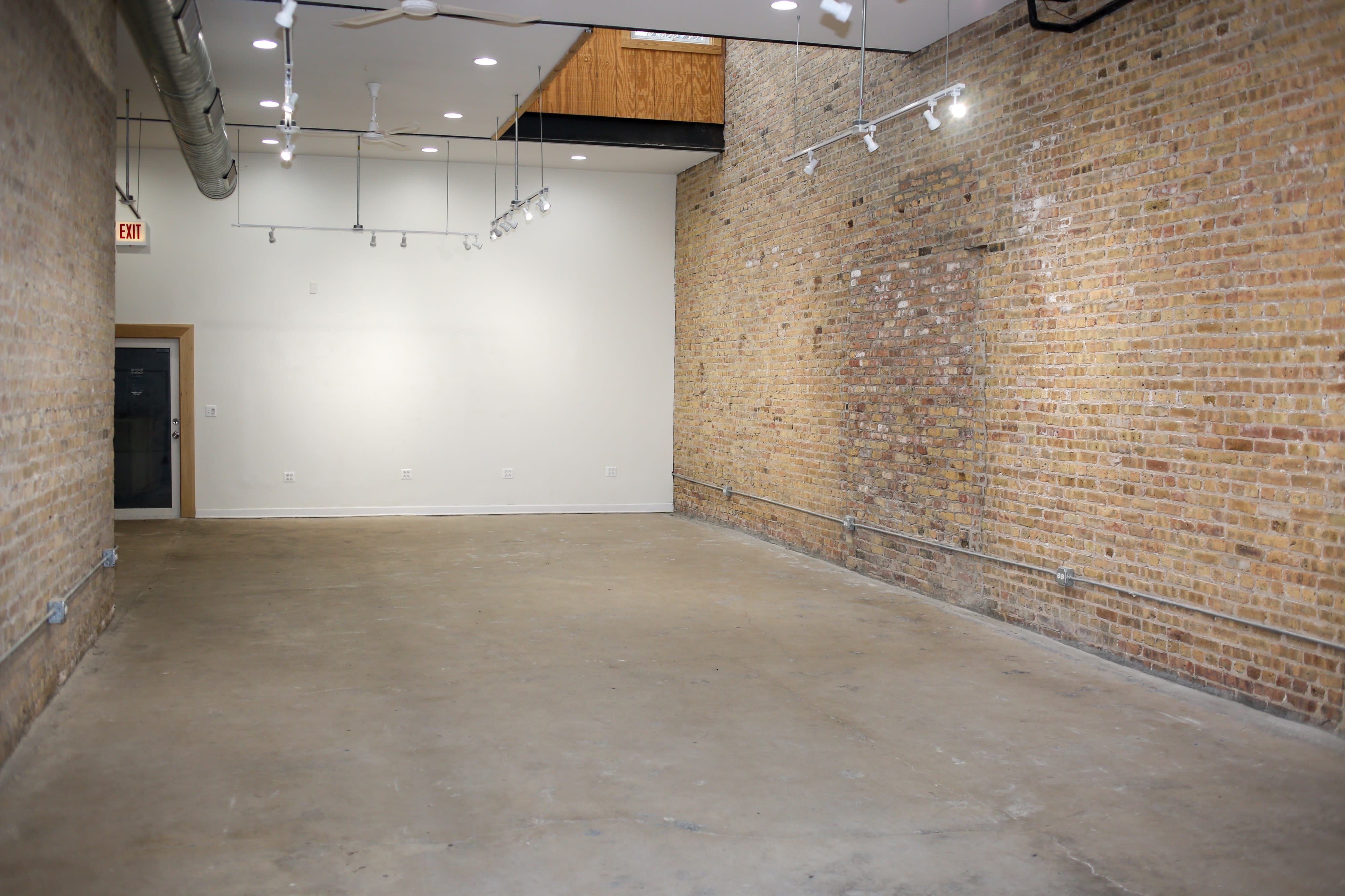 A visitor examines a colorful artwork featuring a woman's portrait at an art gallery with a brick wall backdrop.