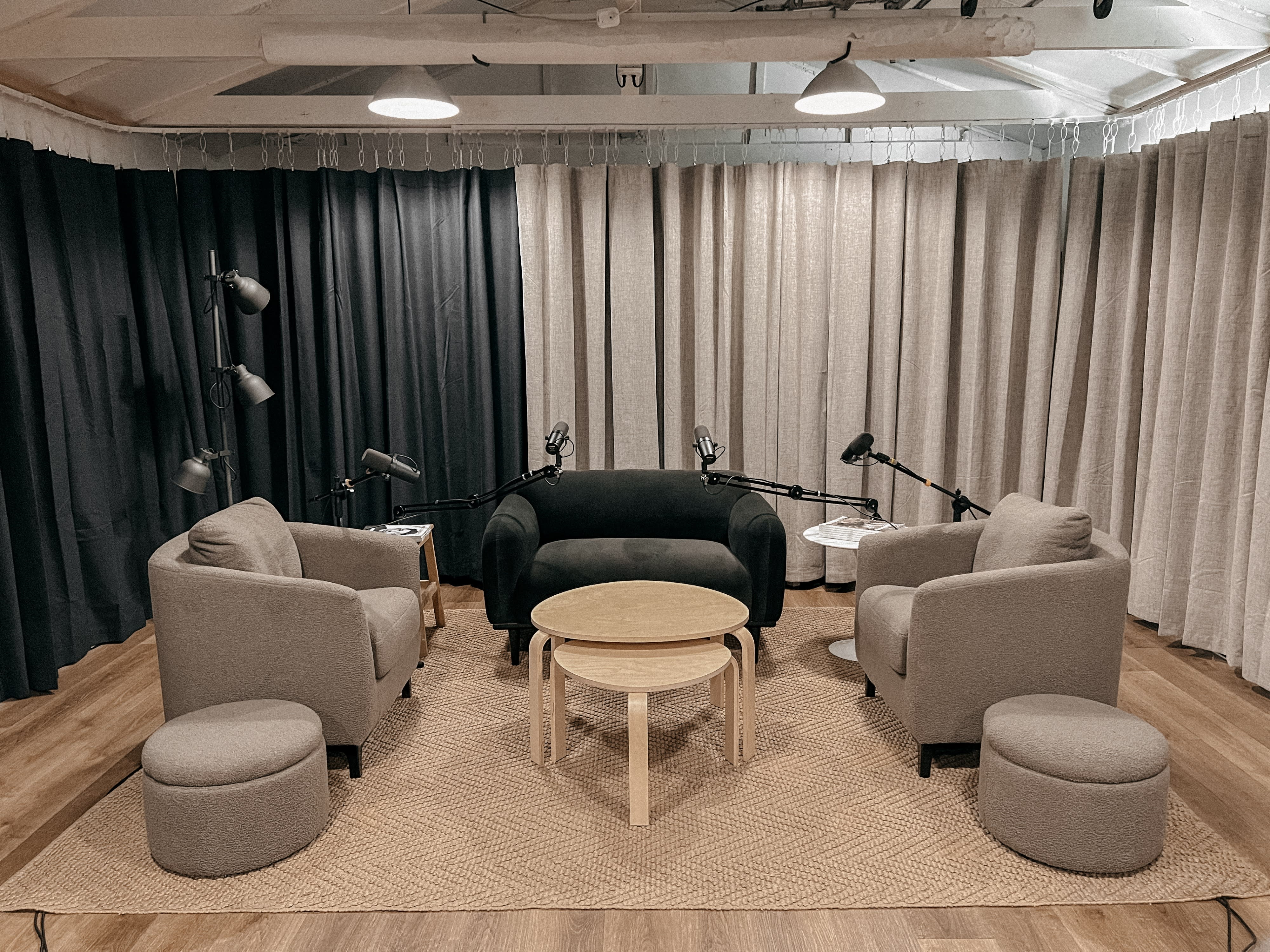 Two men sit in armchairs with microphones in front of them, engaged in a podcast recording.