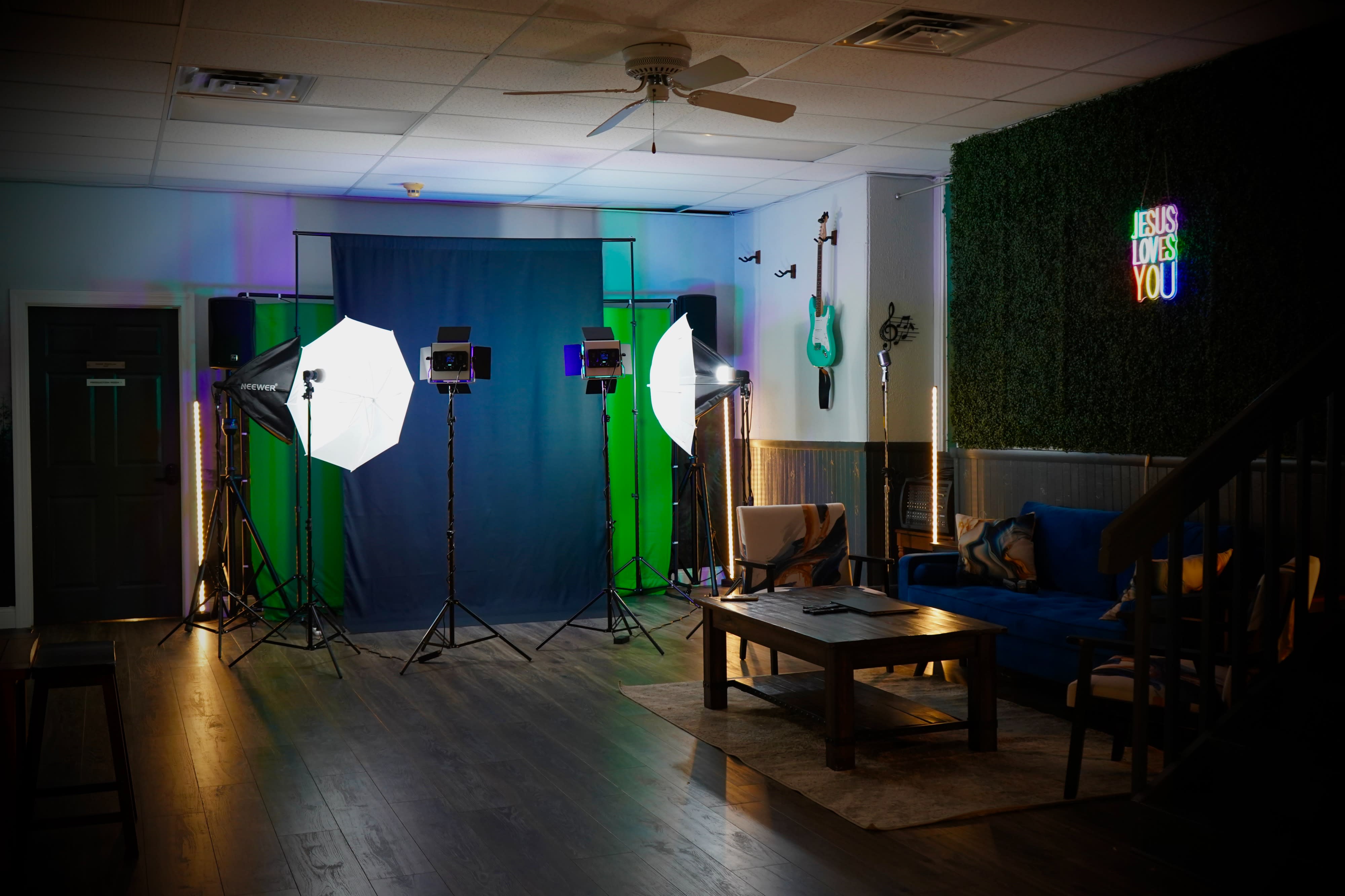 A person adjusts a camera while preparing to record a podcast against a plain background.