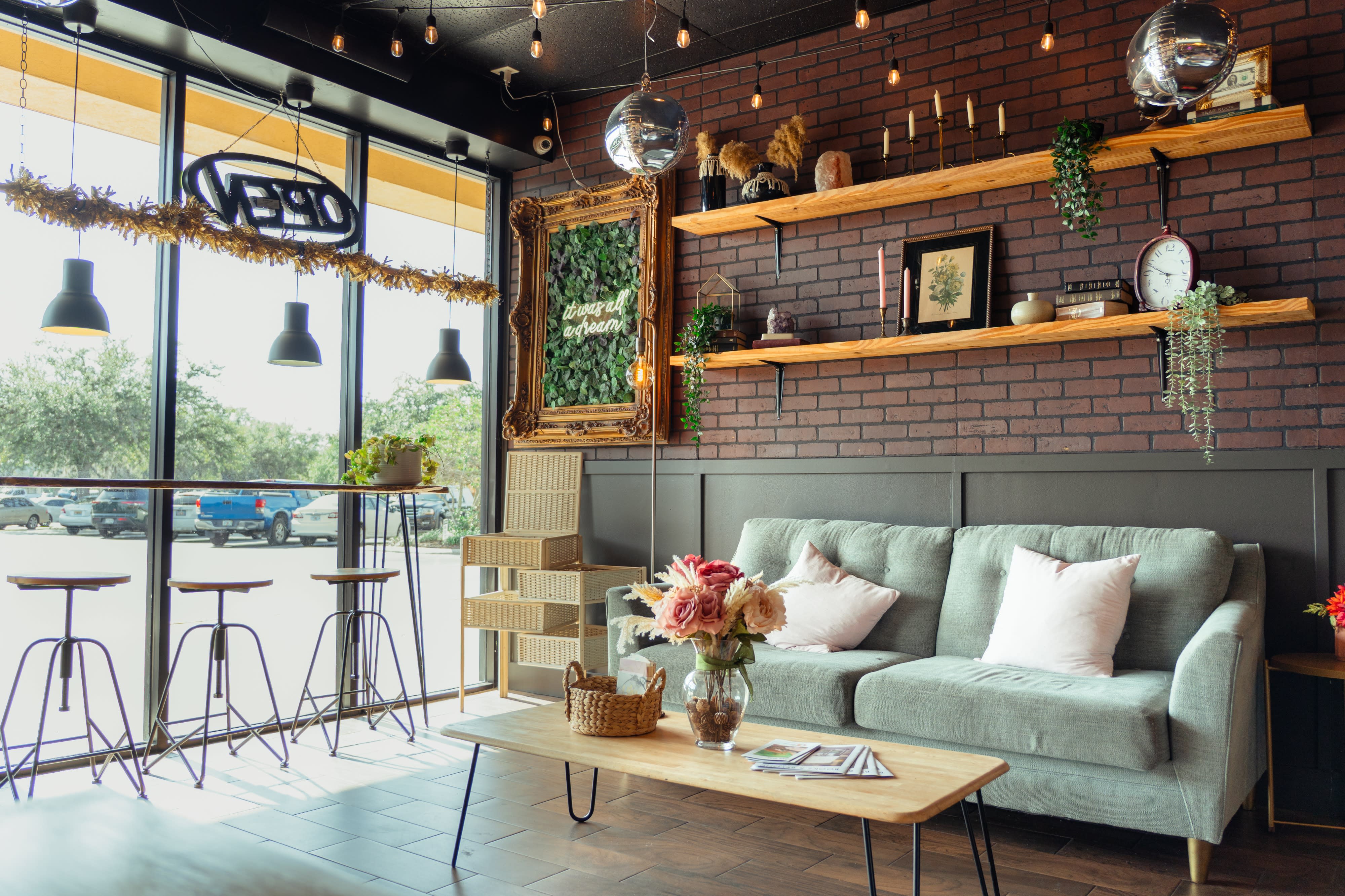 A cozy living room features a "Groovy Baby" banner above a modern couch adorned with colorful pillows, set against a brick wall with shelves displaying decor.