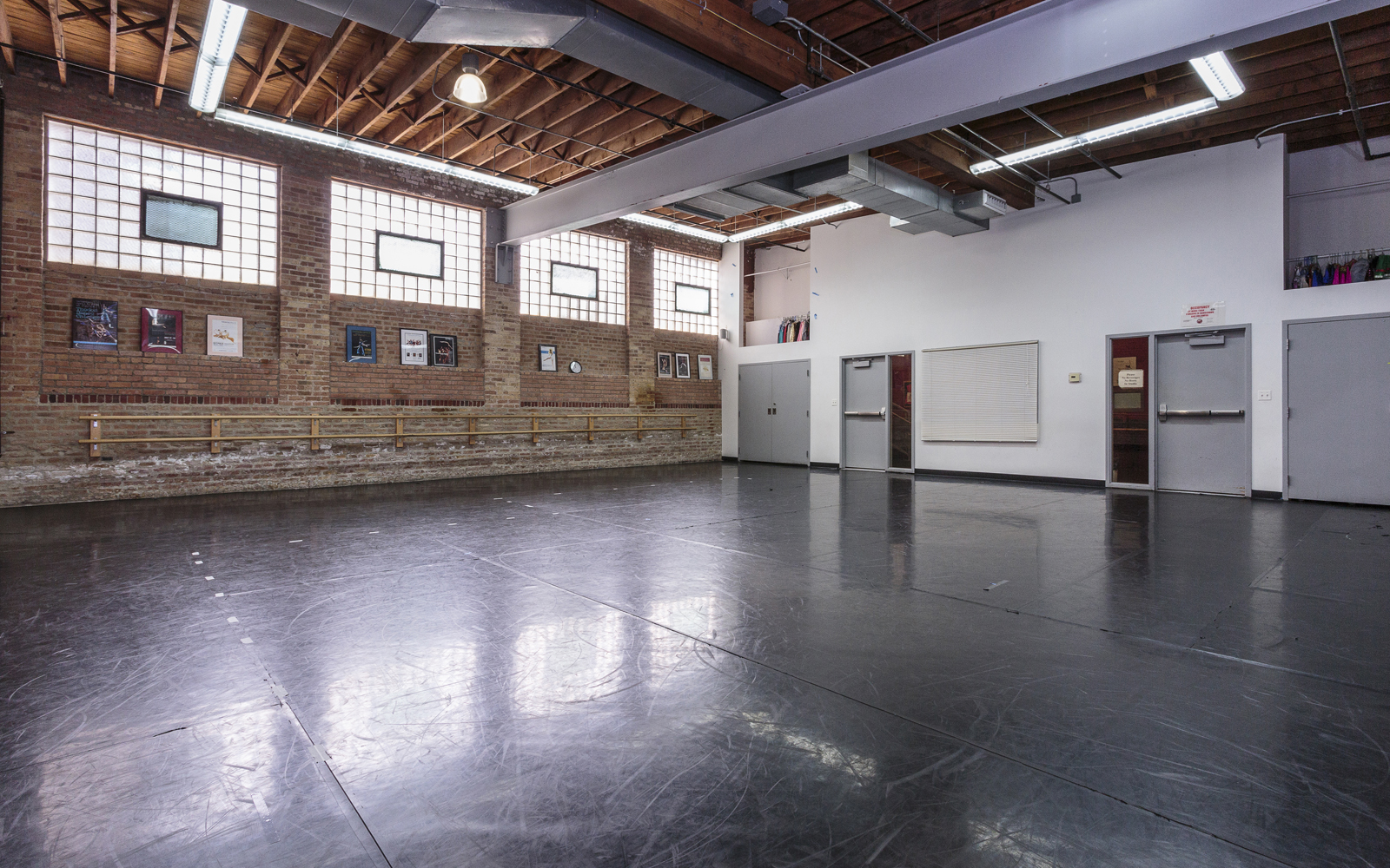 A group of six individuals poses together in a dance studio, showcasing their vibrant workout attire against a brick wall.
