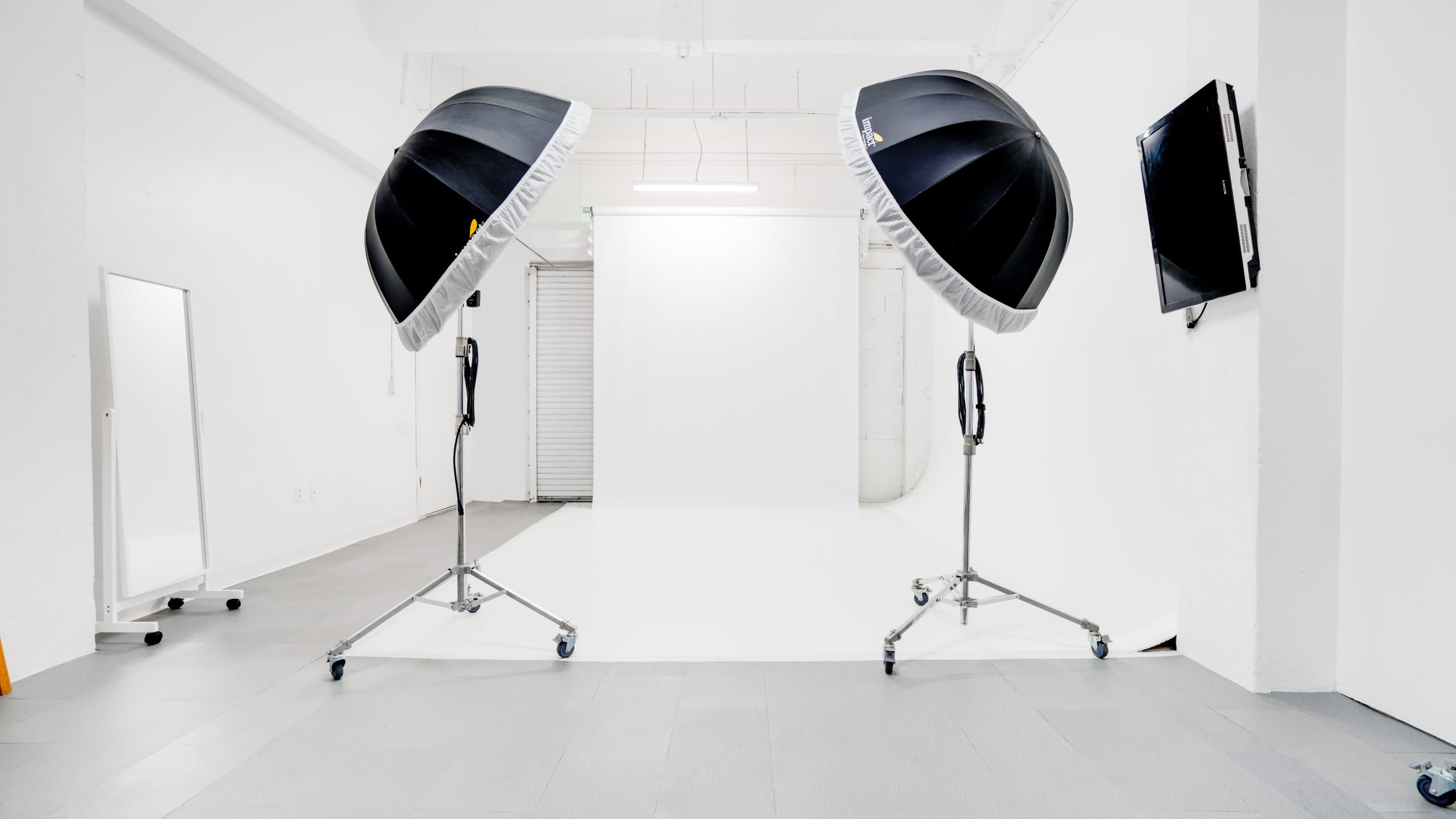 A photographer captures a model seated on a white backdrop while draped in fabric.