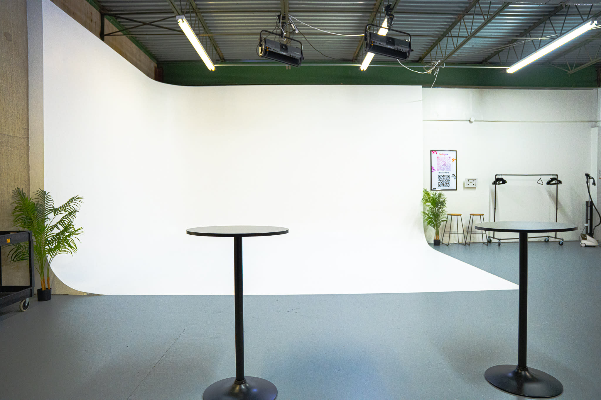 A woman stands in front of a camera setup in a studio equipped with lighting and audio microphones for video production.