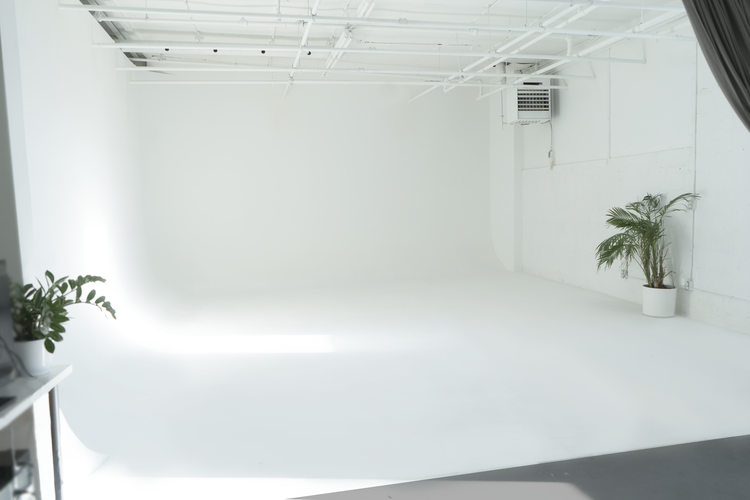 A photographer is capturing images of a model posing in a studio setting with softbox lighting.