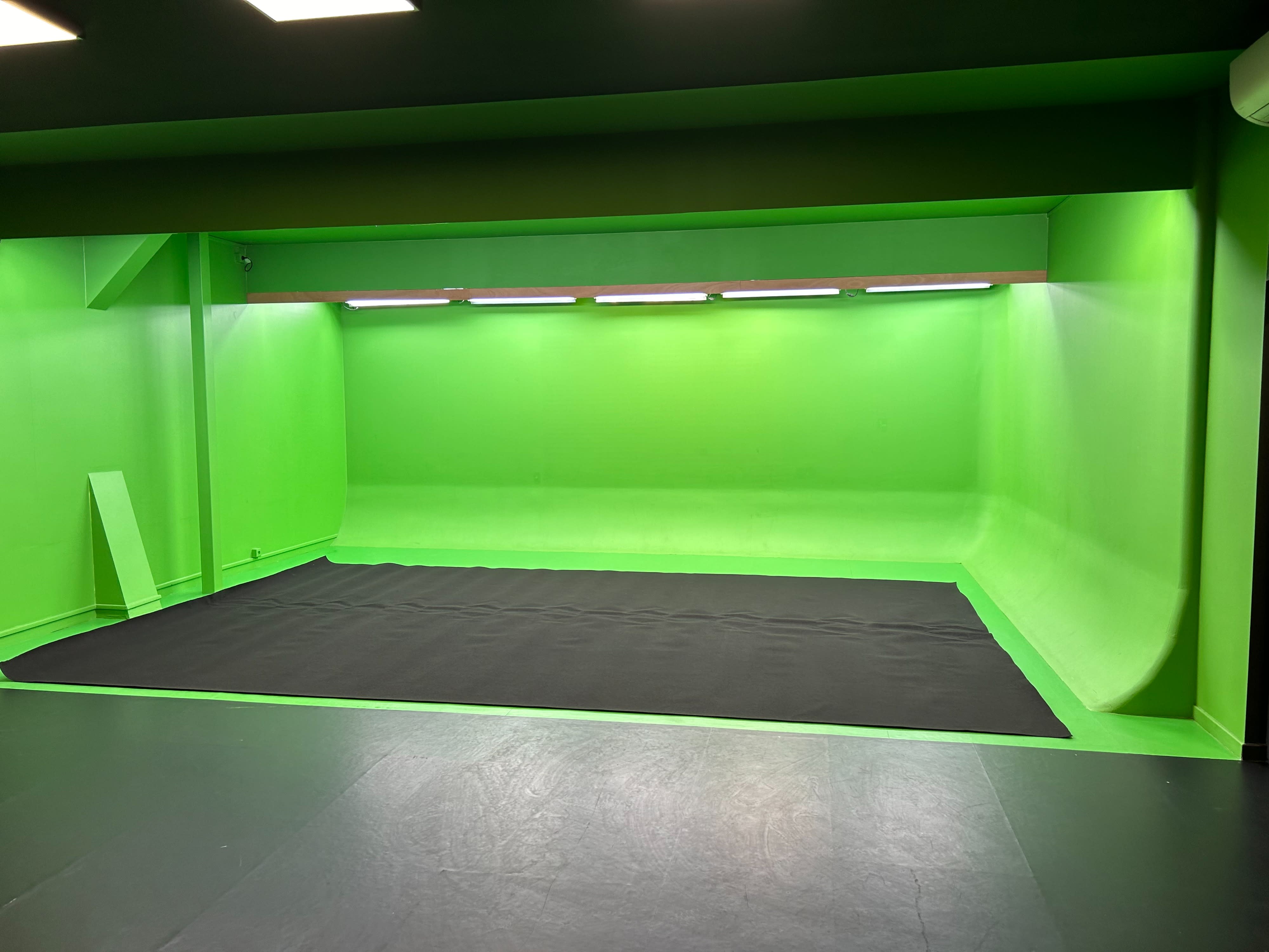 A musician stands on a green screen set, checking their phone while preparing for a rap music video shoot.