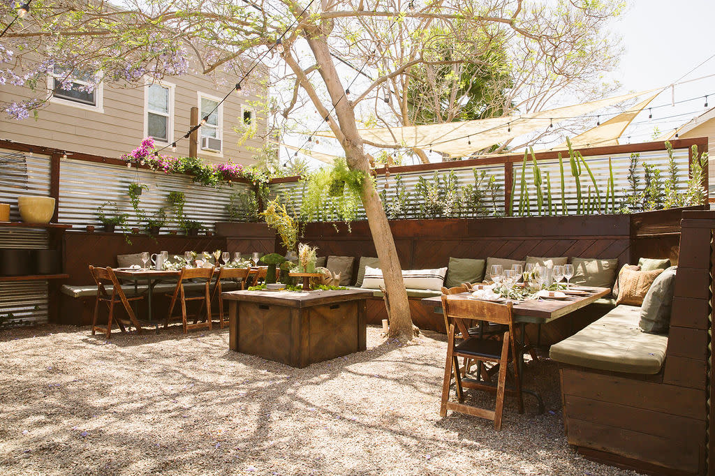 A table is set with slices of bread, a bowl of olive oil, menus, and a small vase of flowers.